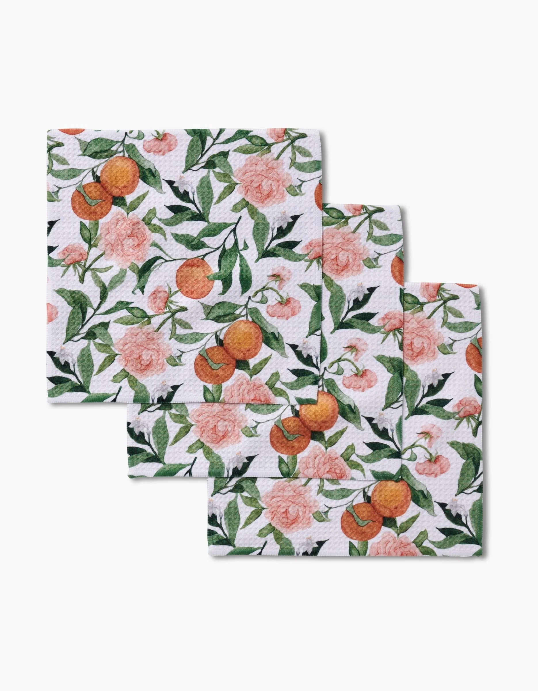 Three reusable Geoweave fabric cloths from Aubrey Fairchild, called Peony For Your Thoughts, feature pink peonies and orange fruits with green leaves, arranged in a staggered stack on a white background.
