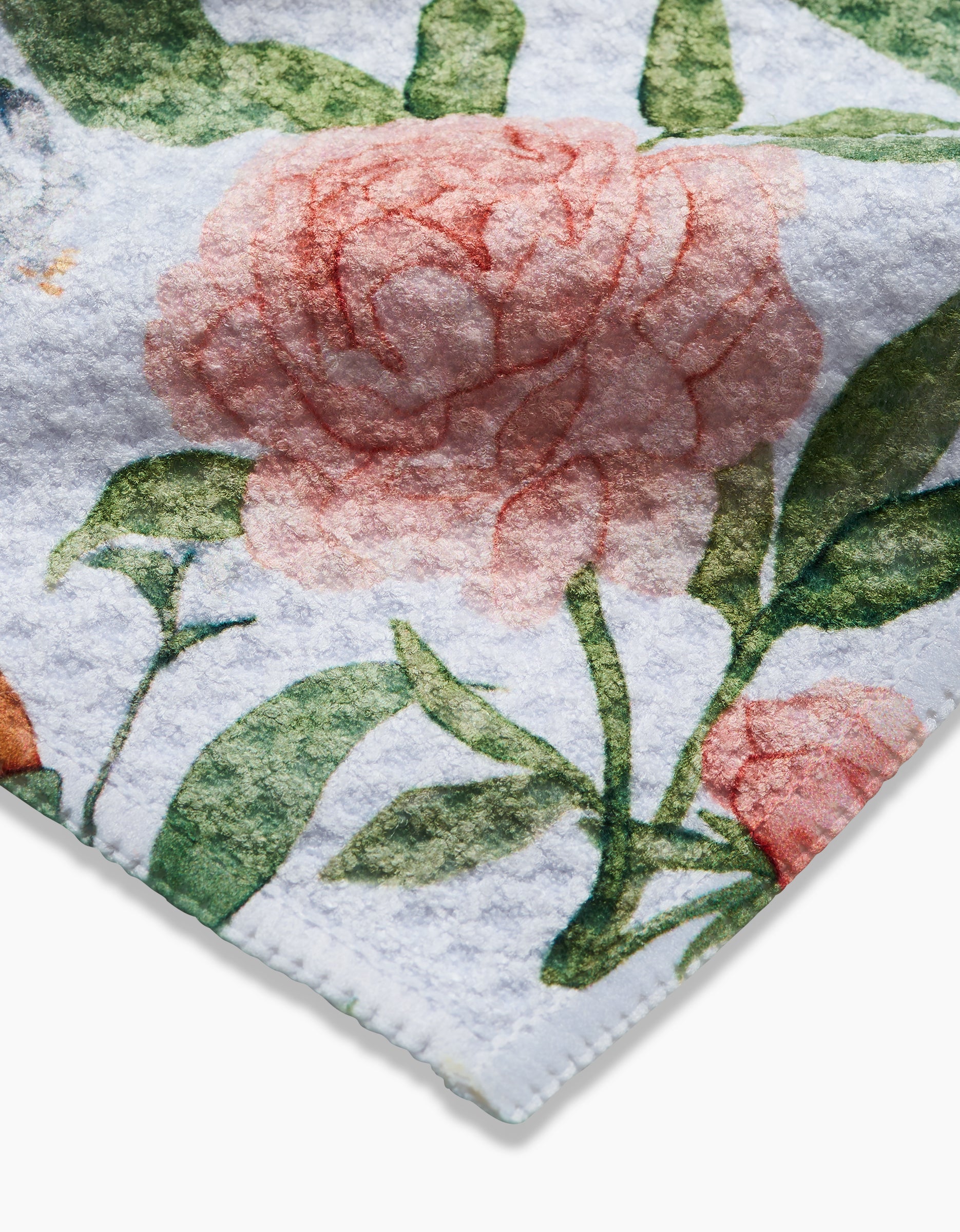 A close-up of Aubrey Fairchild’s “Peony For Your Thoughts,” a white Geoweave fabric made from recycled materials, featuring large pink peonies and green leaves with a soft, textured surface and neatly stitched edges.