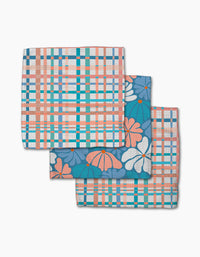 Four folded cloth napkins by Rachel Parker, from the Picnic Flowers collection—two with a blue, orange, and white plaid and two with a blue floral design—are made from super-absorbent recycled materials.