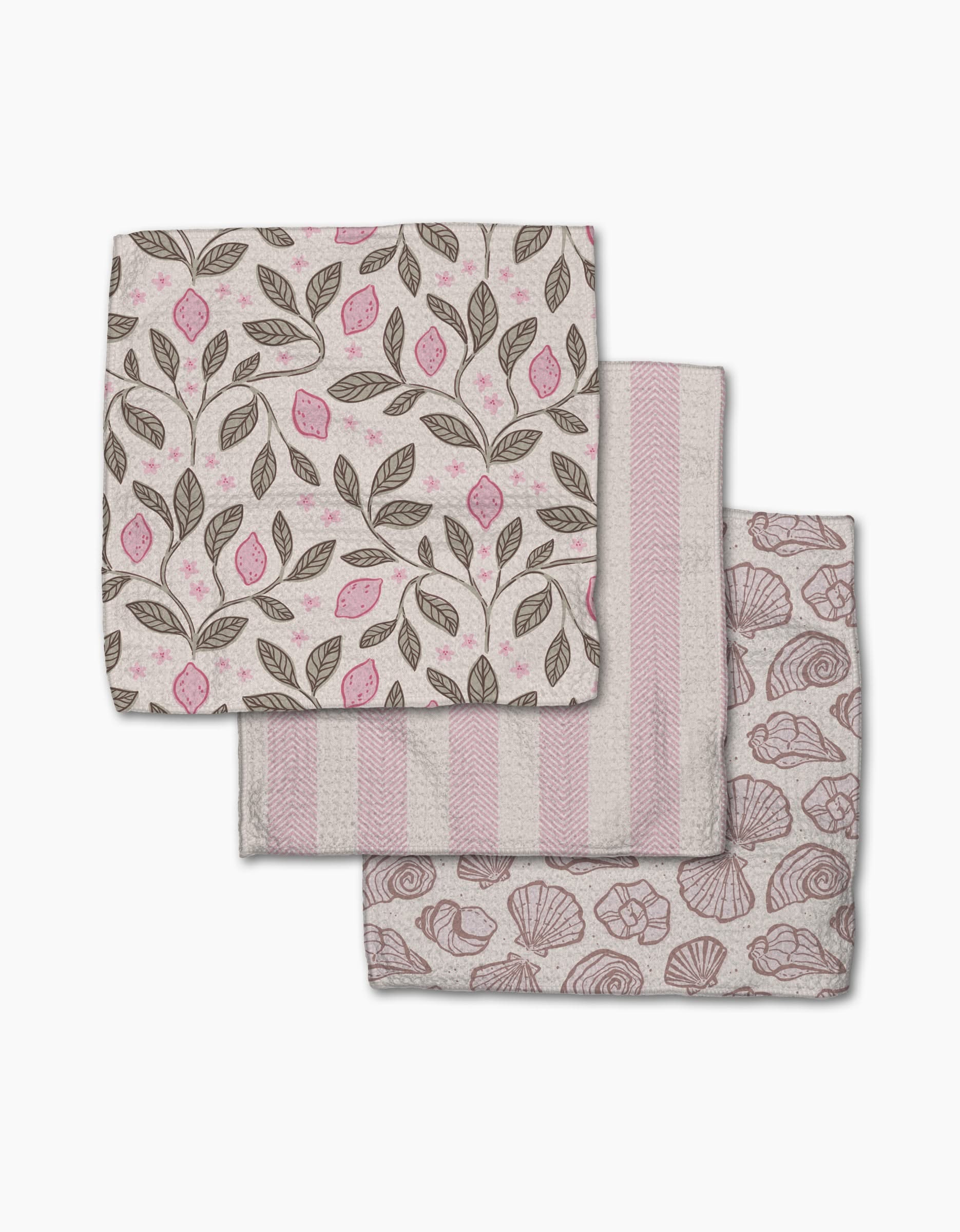 Three folded Pink Summer cloth napkins by Teri the Butter—one with pink and brown leaf and lemon print, one with pink and white stripes, and one with a pink seashell design—are arranged on a white background.