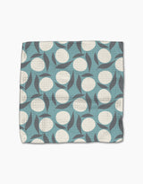 The Polka Dot Blooms quilted dishcloth set by Lizzie Clark is made from recycled materials and features a blue background with white circles and overlapping gray leaves.