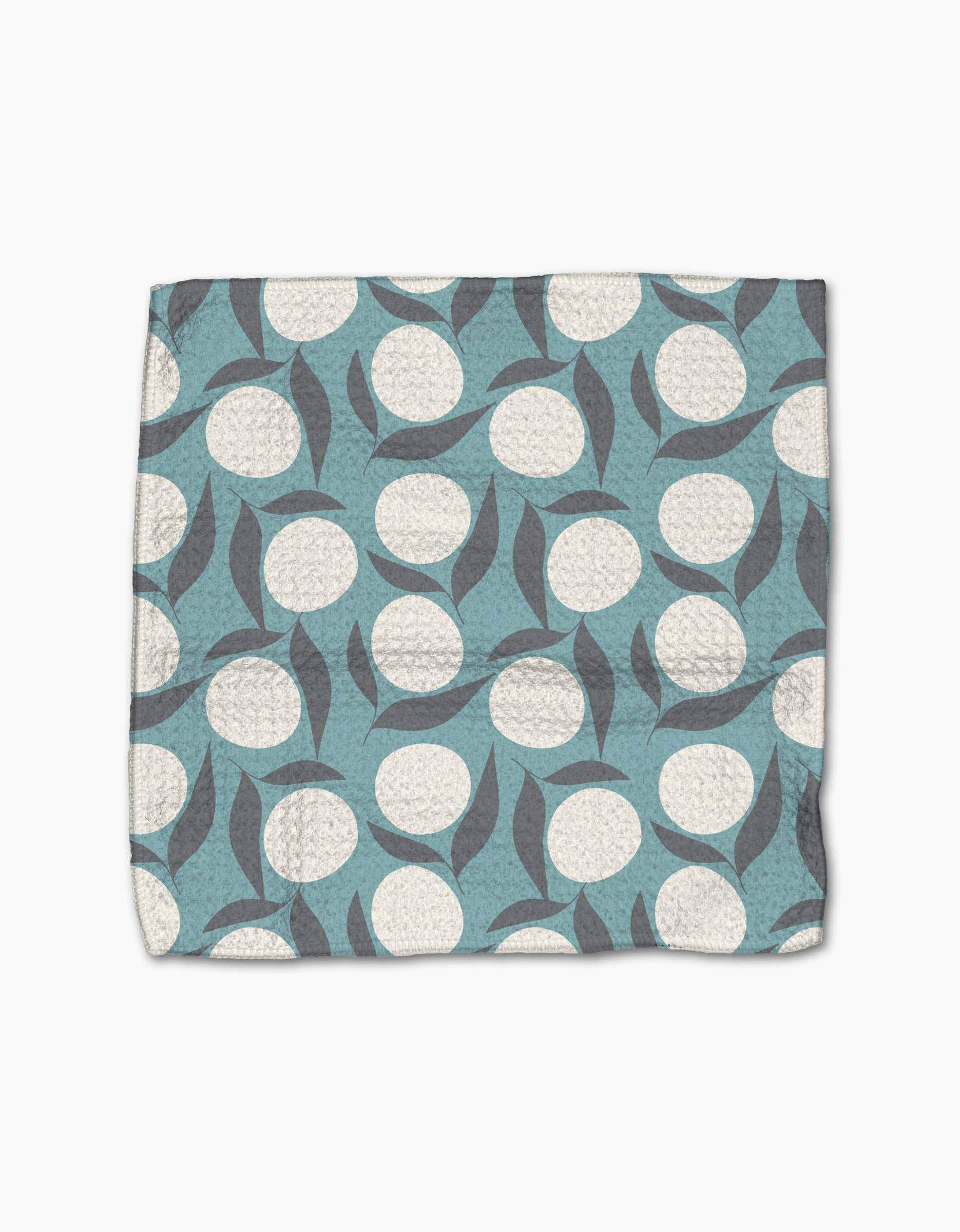 The Polka Dot Blooms quilted dishcloth set by Lizzie Clark is made from recycled materials and features a blue background with white circles and overlapping gray leaves.