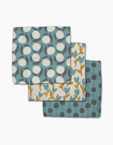 Polka Dot Blooms by Lizzie Clark includes three folded tea towels made from recycled materials, each featuring unique botanical patterns in blue, yellow, and white.