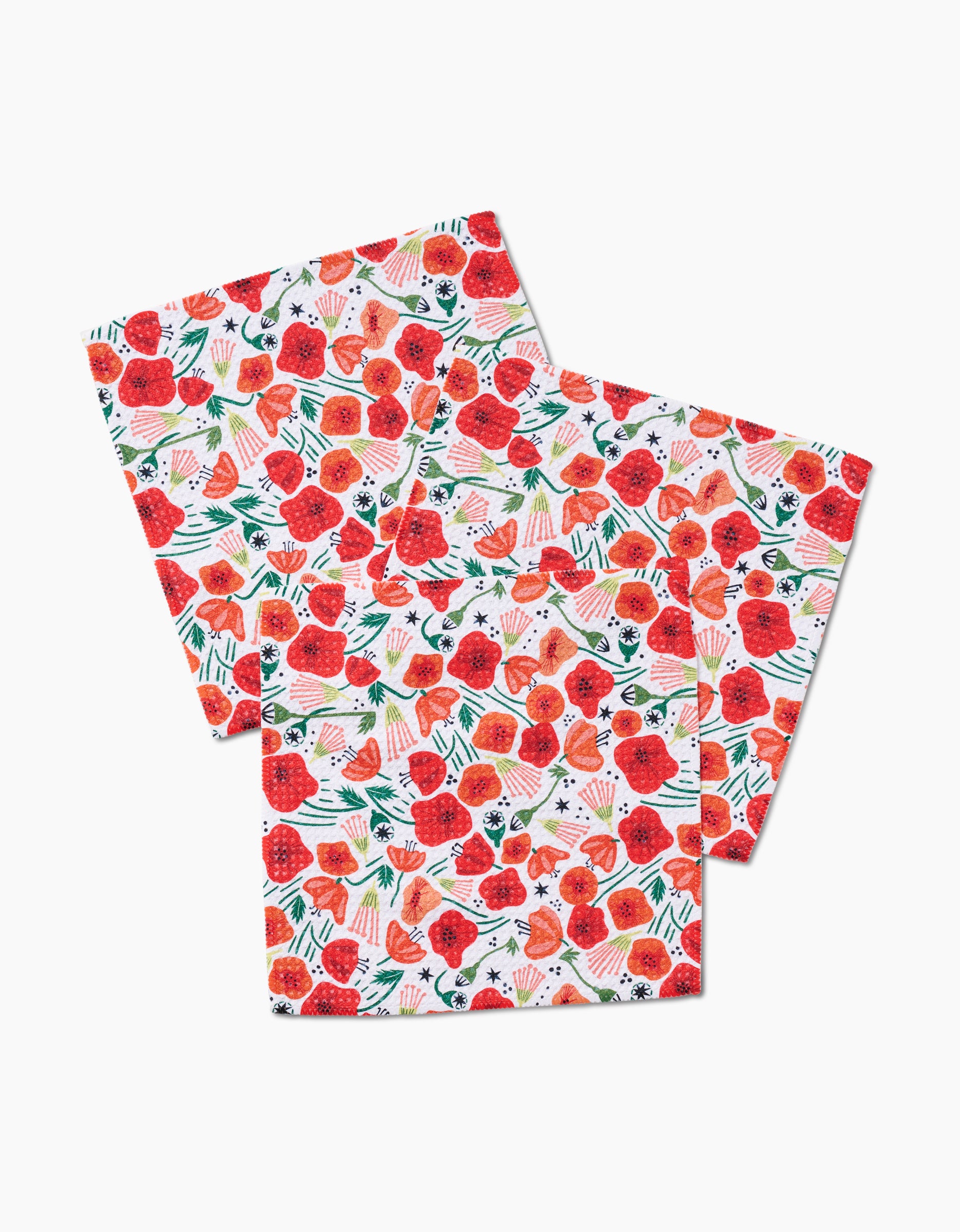 Three square Poppy Power napkins by Elisabeth Wing, made from recycled materials, display a vivid pattern of red strawberries, green leaves, and white flowers on a white background, shown overlapping on a plain surface.