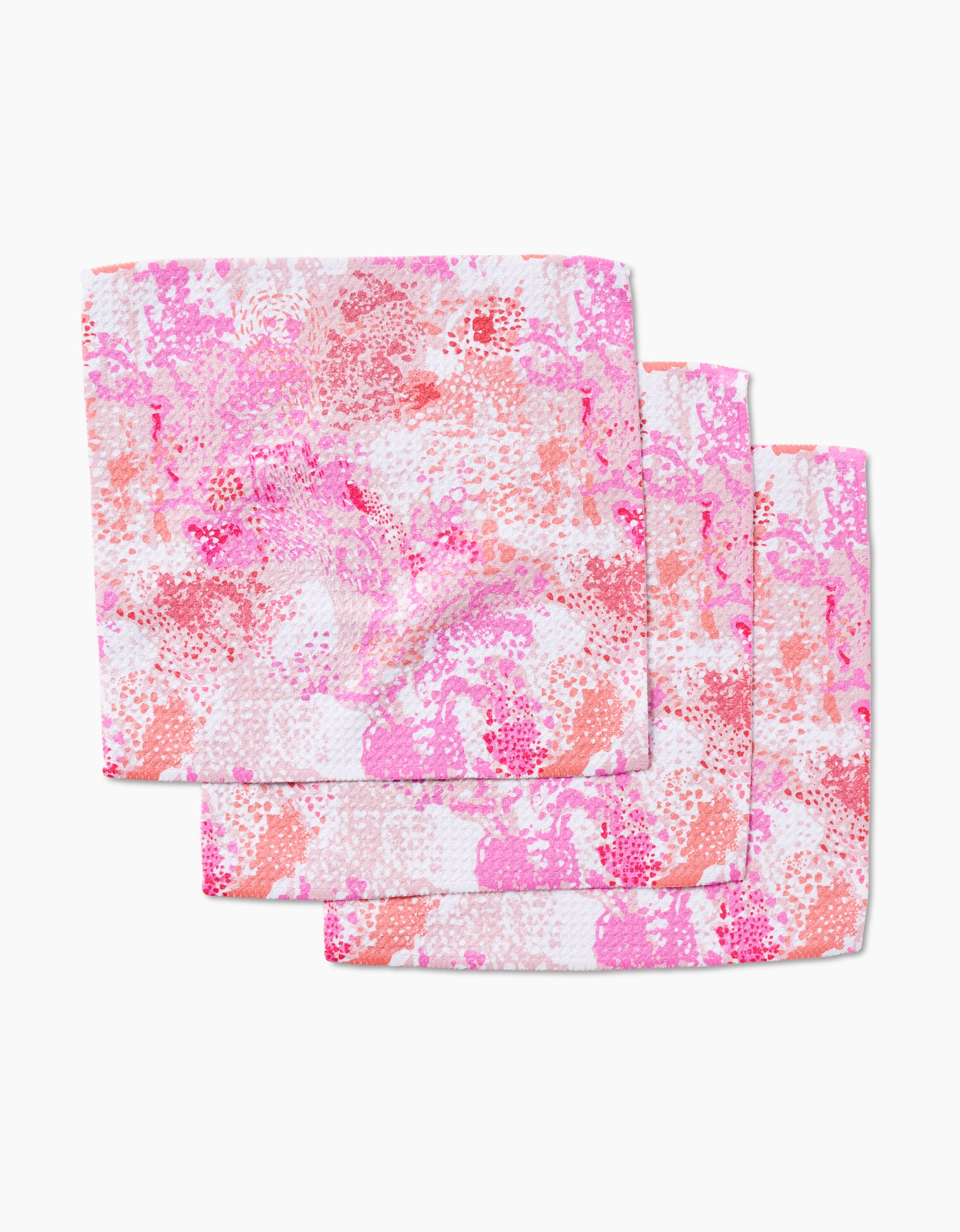Three Rawhide dishcloths by Elisabeth Wing, crafted from Geoweave fabric and showcasing an abstract pink, red, and white pattern, are stacked with slight overlap on a white background.