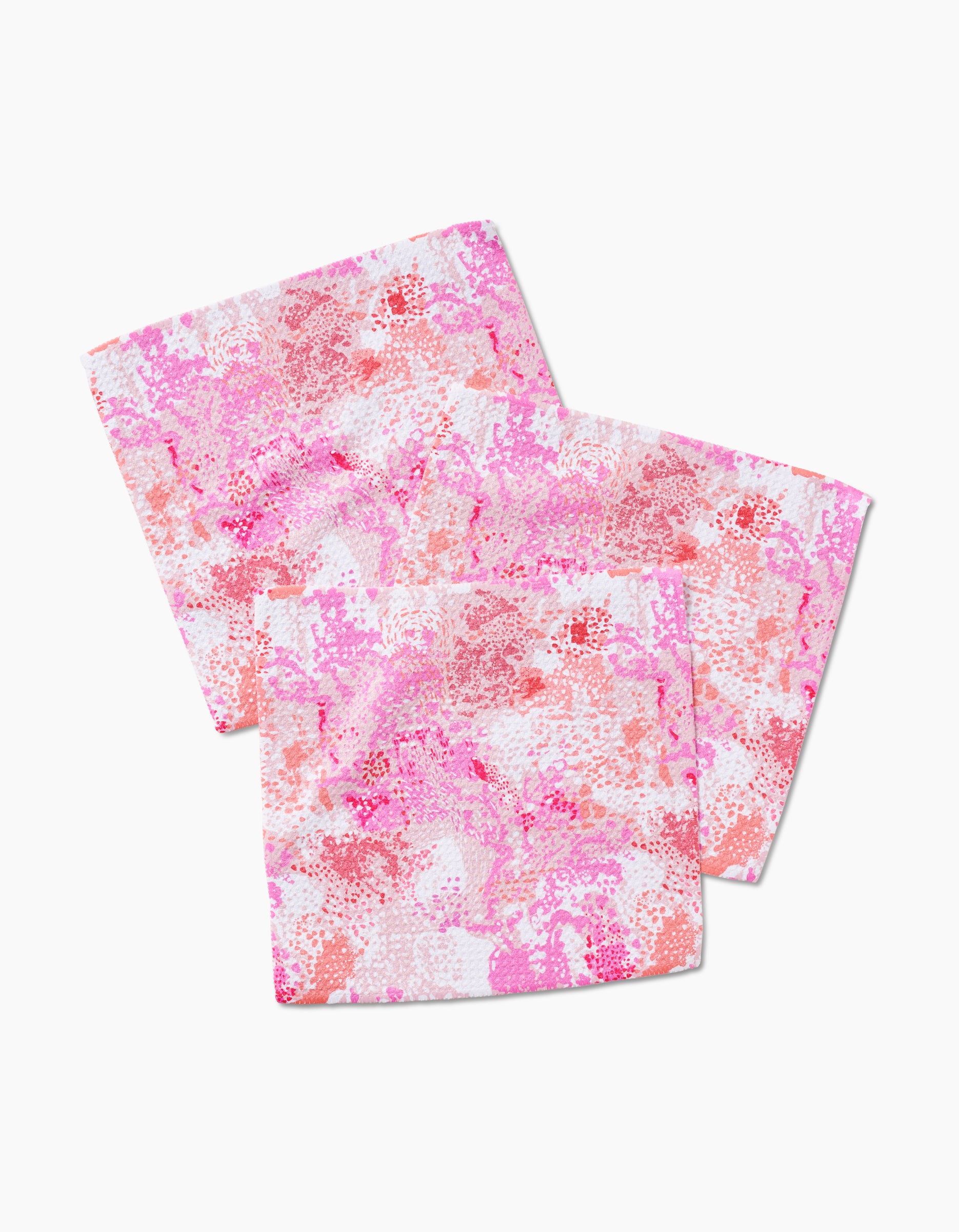 Two folded Rawhide napkins by Elisabeth Wing, featuring pink, red, and white abstract patterns on Geoweave fabric, are slightly overlapping on a white background.