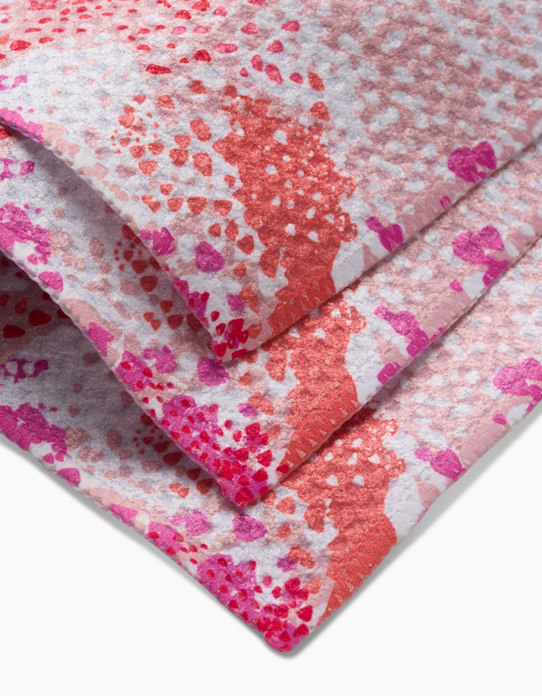 Three folded Rawhide dishcloths by Elisabeth Wing feature a textured Geoweave surface with vibrant red, pink, and purple dots and splotches on a white background.