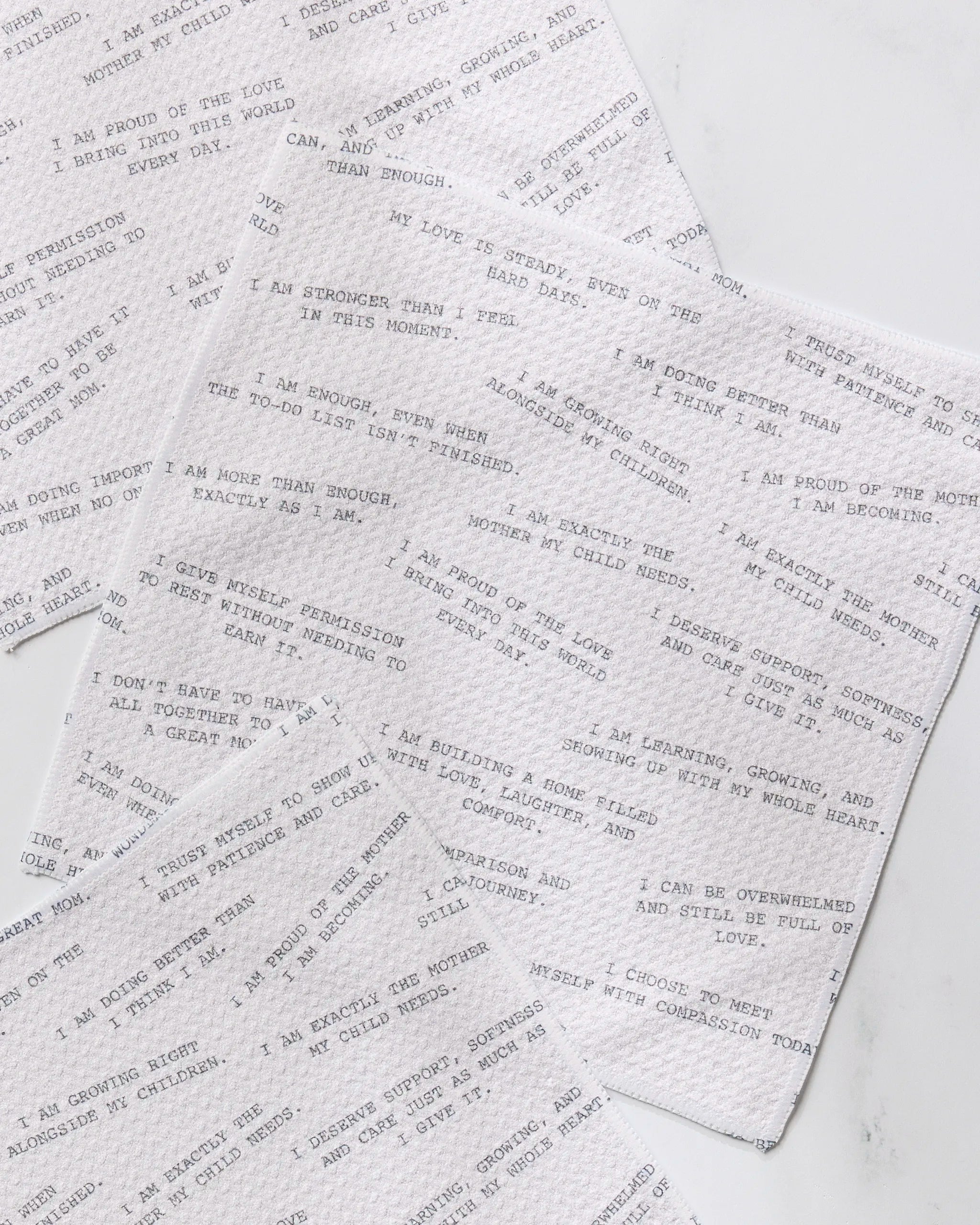 Geometry’s Reminders for Mom napkins, crafted from recycled materials, display affirming phrases like “I am enough” and “I am strong,” overlapped on a white surface for an uplifting, eco-friendly accent.