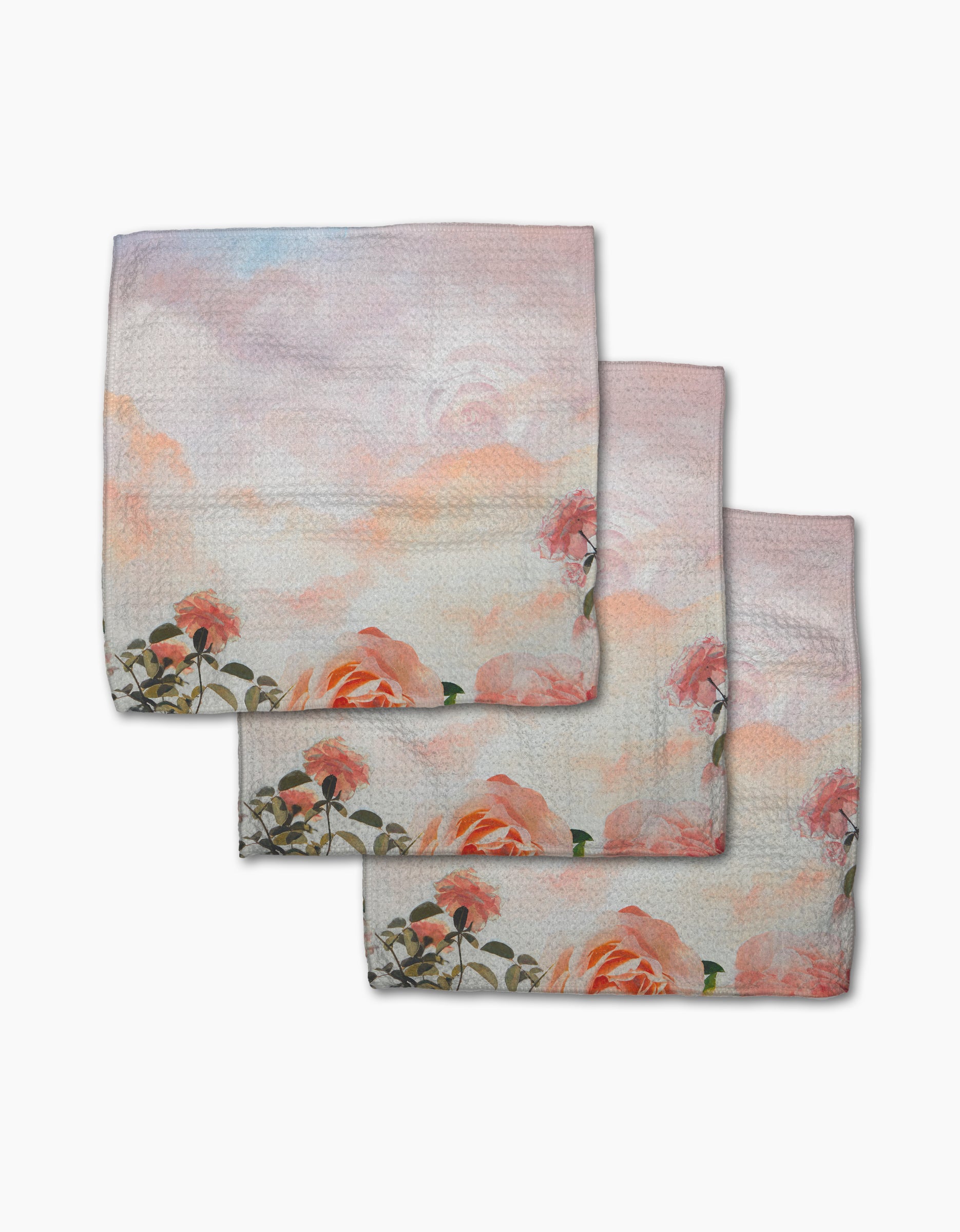 The Rhapsody in Bloom dishcloth set by Stefanie Bales features three pastel recycled towels with watercolor-style pink and peach roses, green leaves, and a soft pink-blue sky. Absorbent and stylish—perfect for any kitchen.