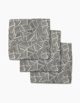 The Rhythm Current Stripes dishcloth set by Sarah Daugherty features three folded rectangular napkins with a black and white geometric pattern, made from recycled materials for a chic, eco-friendly addition to your home.
