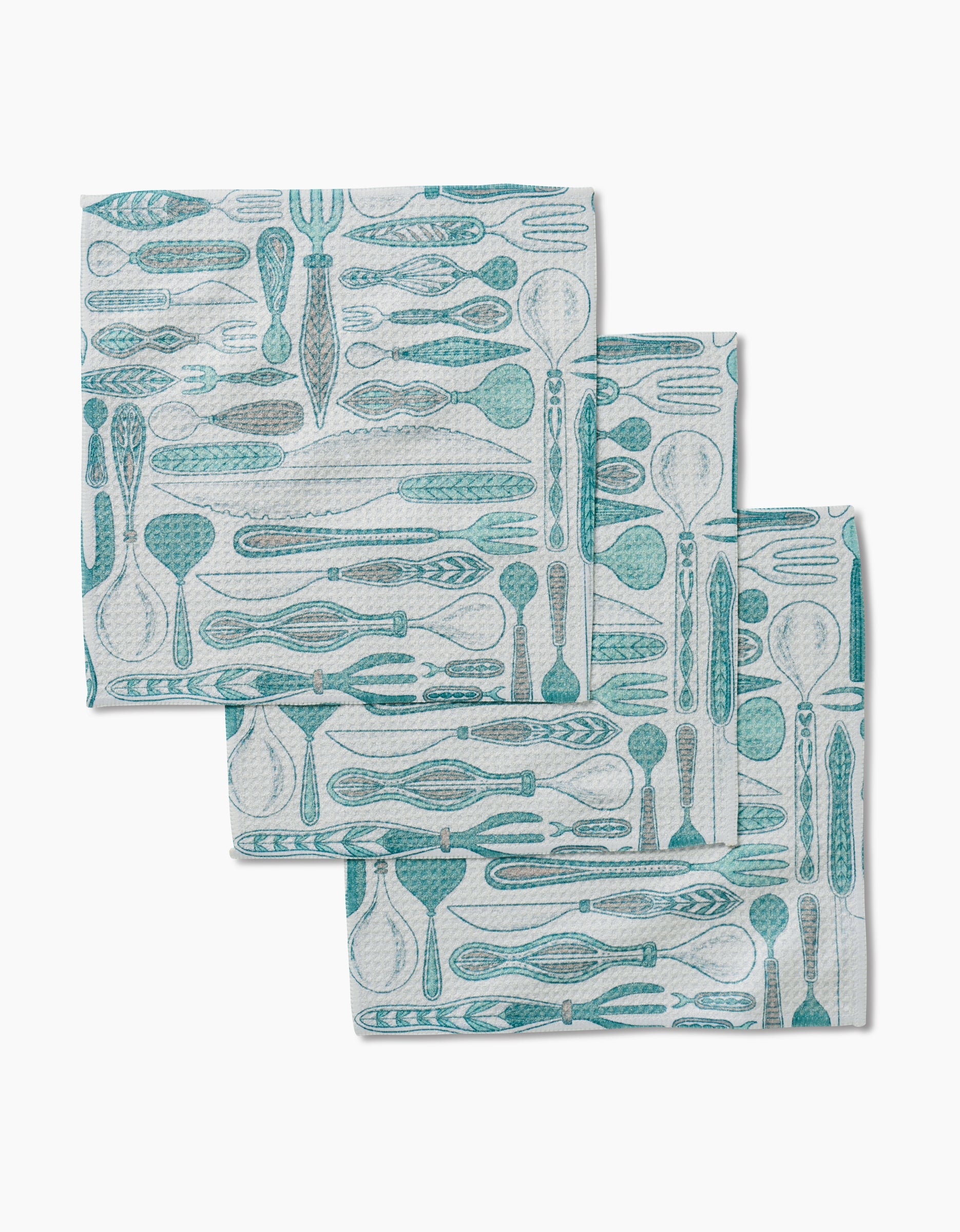 Three folded Romy Wares kitchen dishcloths by Amy MacCready, featuring a blue and gray utensil pattern with spoons, forks, and knives, are neatly stacked in an overlapping arrangement on a white background.