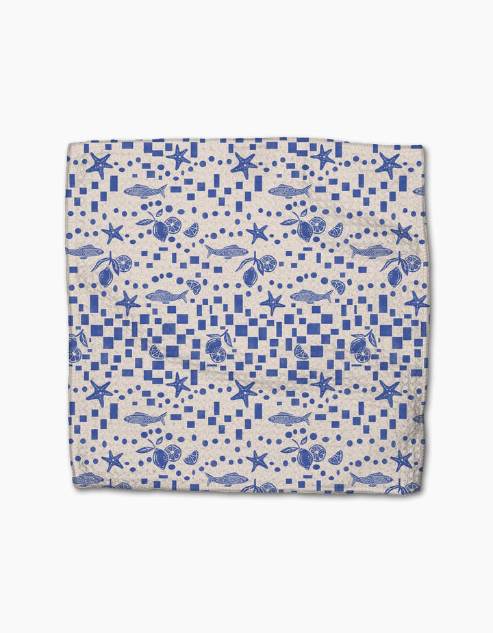 The Santorini Tile dishcloth by Geometry features a blue nautical seashell and starfish pattern with geometric shapes on white, crafted from durable Geoweave fabric for superior cleaning.