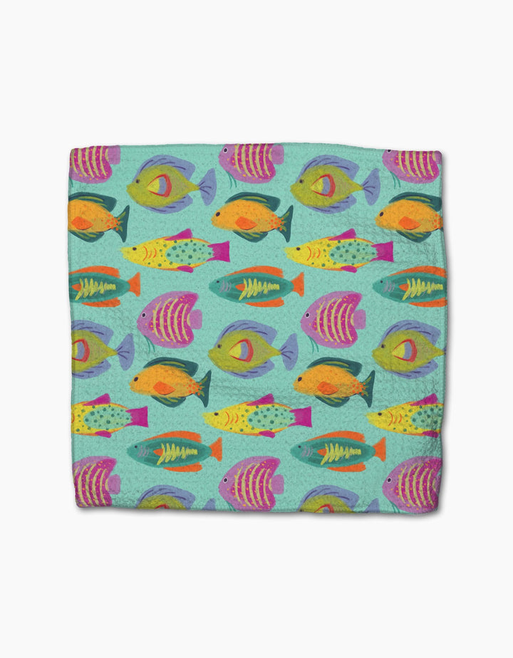 The Geometry Schooling blanket is super-absorbent and features a vibrant design of colorful fish in orange, yellow, purple, pink, and green swimming on a light teal background.