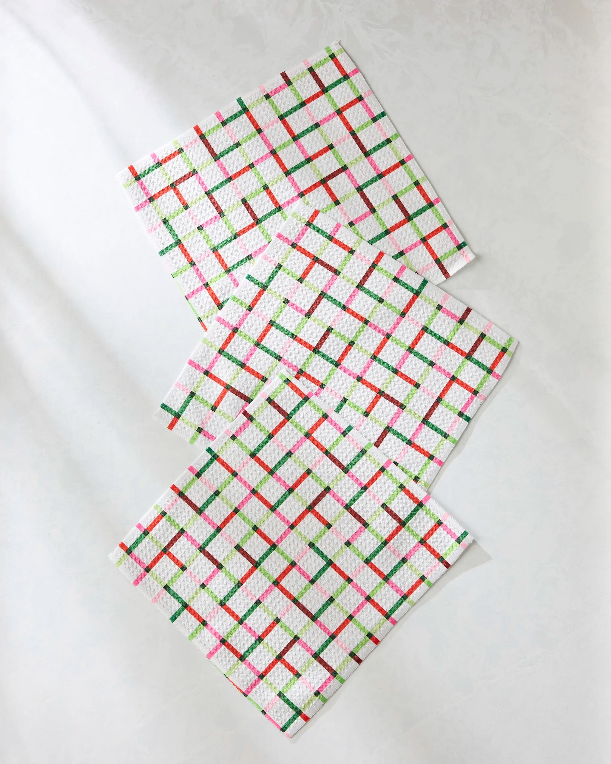 The Geometry Season of Joy dishcloth set includes three super-absorbent towels with a festive plaid design in red, green, and pink diagonal lines on a light background.