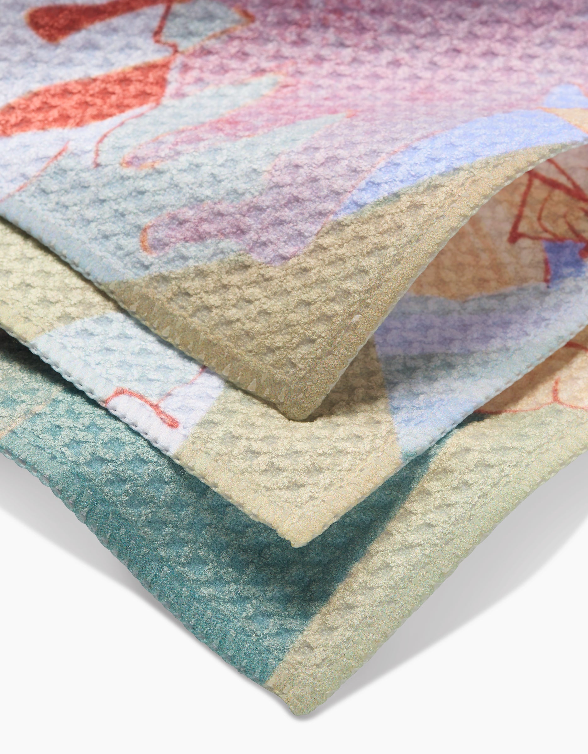 A close-up of Secret Fort by Kristina Baker shows its folded Geoweave fabric, featuring a colorful abstract pattern in purple, pink, blue, green, and beige. The waffle-like texture makes it perfect for stylish dishcloths.