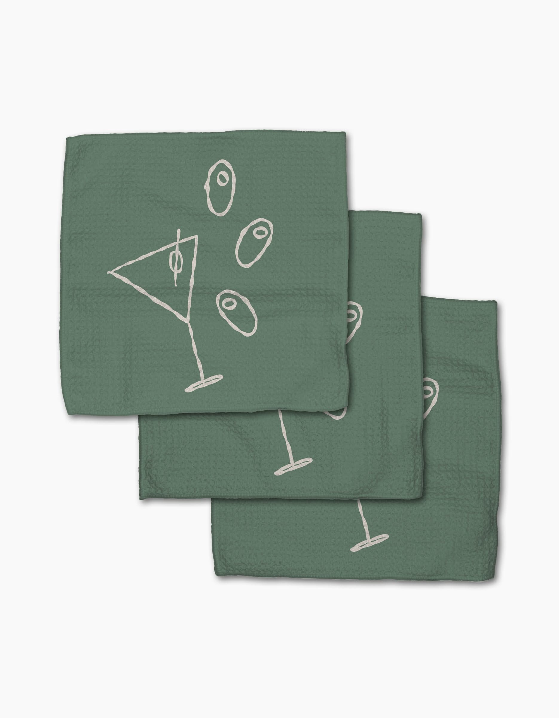 Three green Shaken Not Stirred cocktail napkins by Rosa Kichline, made from recycled materials, feature a white line martini glass and three olives design, arranged in a slightly overlapping stack on a white background.