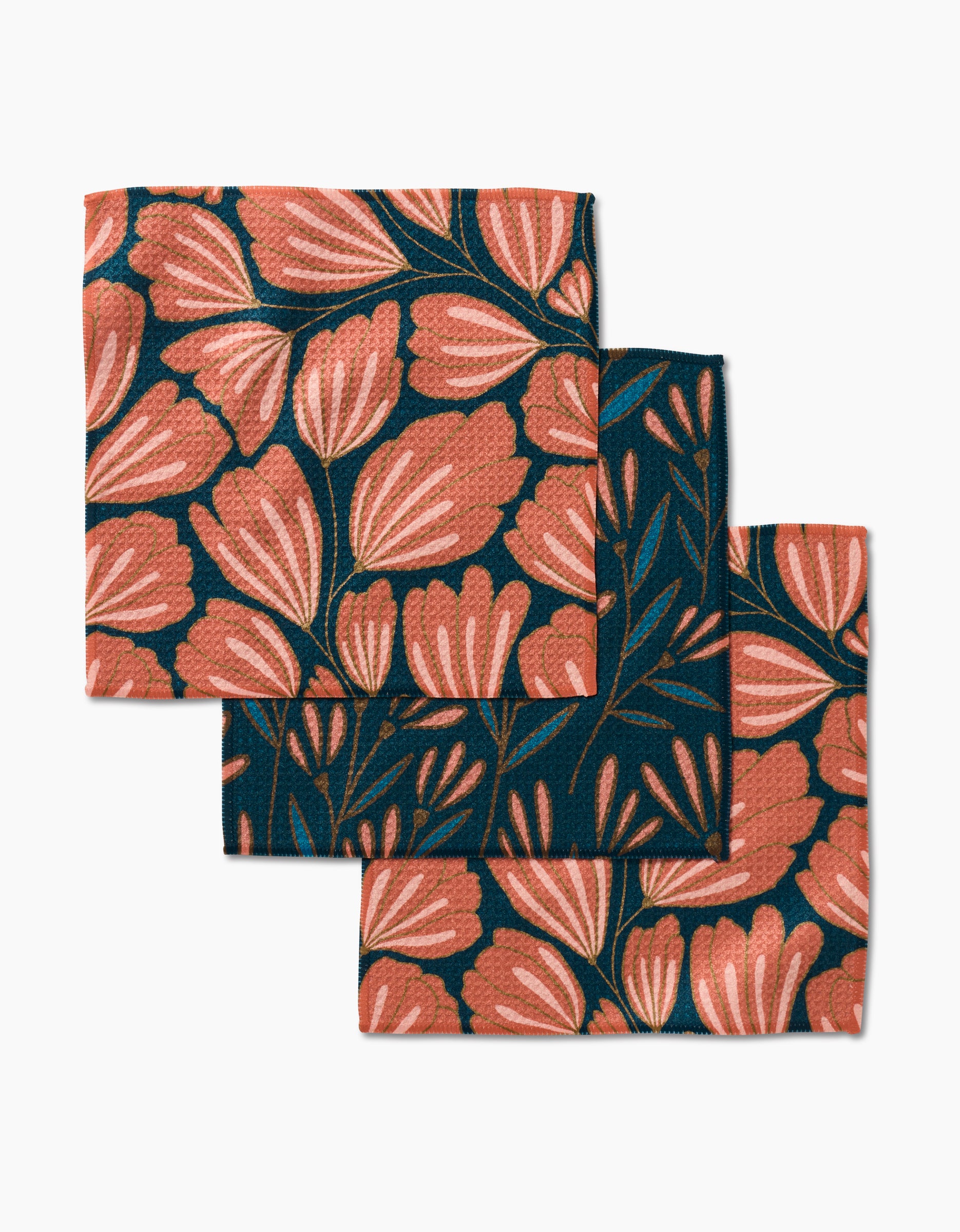 The Sheila Flower set by Amy MacCready includes three square fabric napkins made from recycled materials, each with large pink and coral floral patterns and dark green leaves on a deep navy blue background.
