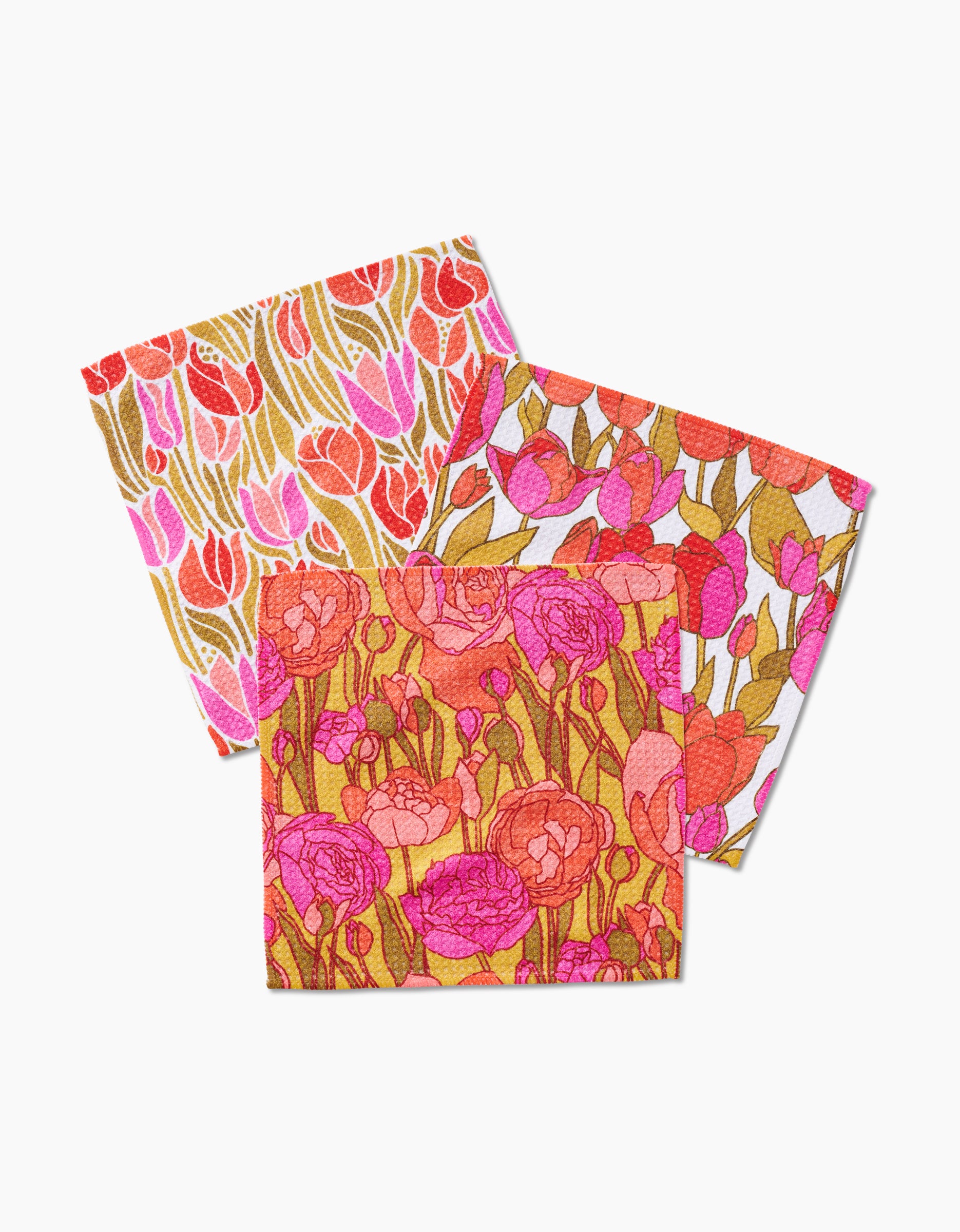 The Sidney dishcloth set by Amy MacCready features three colorful square Geoweave cloths with floral patterns in pink, red, orange, and gold—showcasing tulips and other blooms overlapping on a white background.