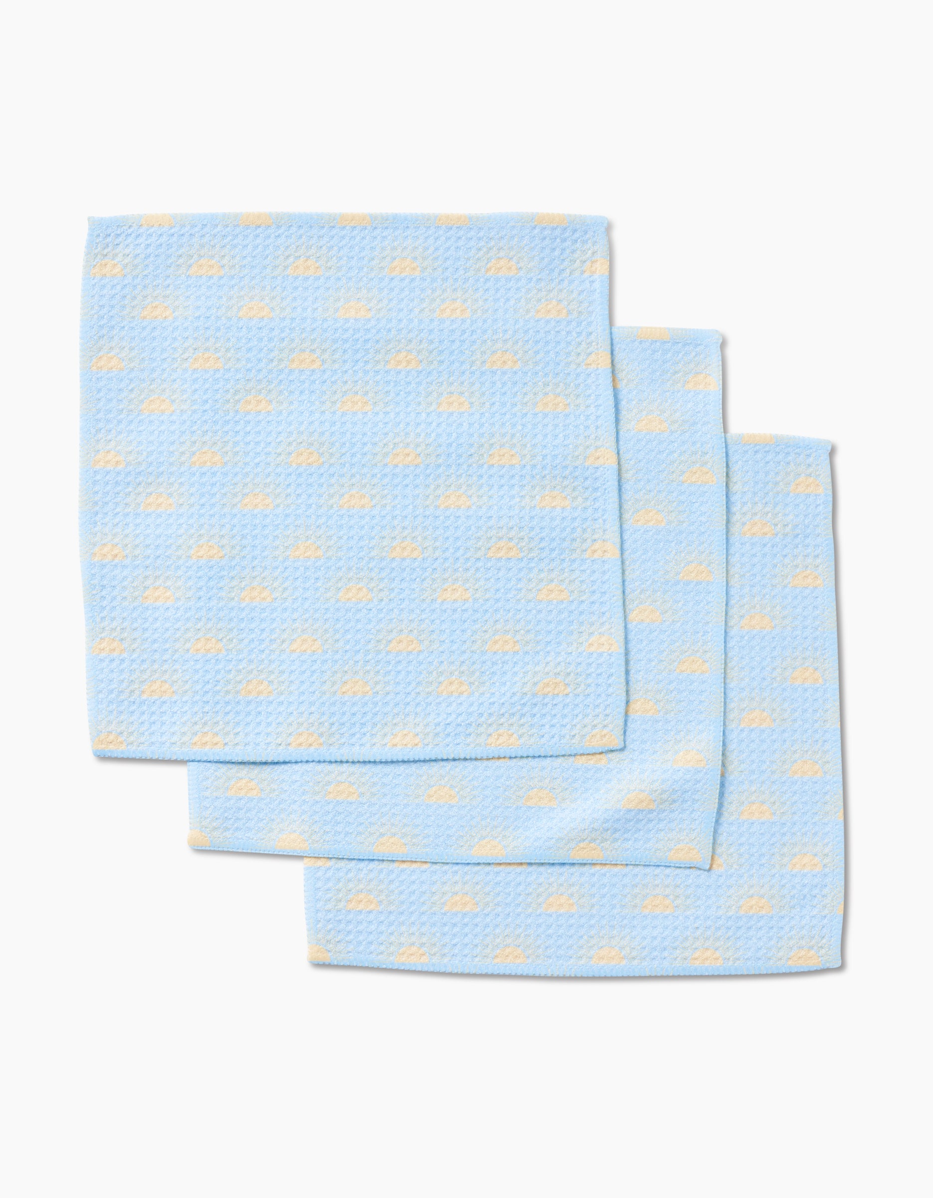 Three Soft Summer Sun cloths by GEOMETRY, made from super-absorbent Geoweave fabric in light blue with a textured surface and small cream-colored clouds, are stacked in a slightly overlapping arrangement on a white background.