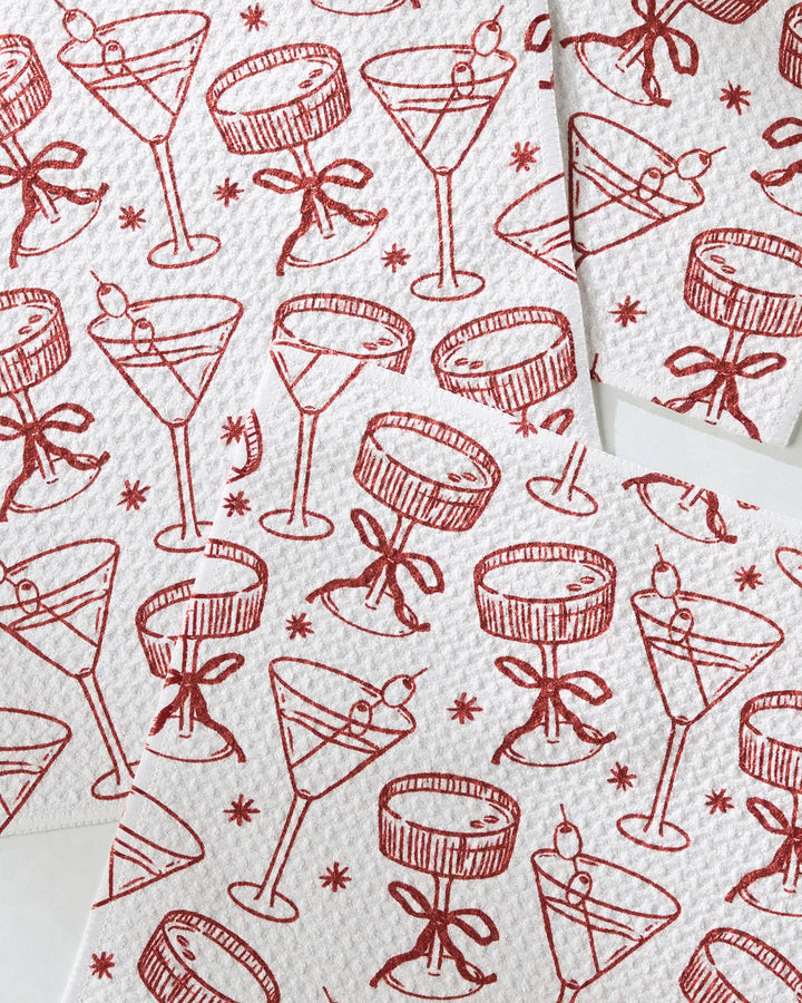Soiree napkins by Geometry feature red line drawings of cocktail glasses—some with cherries, others with bows—on white recycled material, arranged in an overlapping pattern.