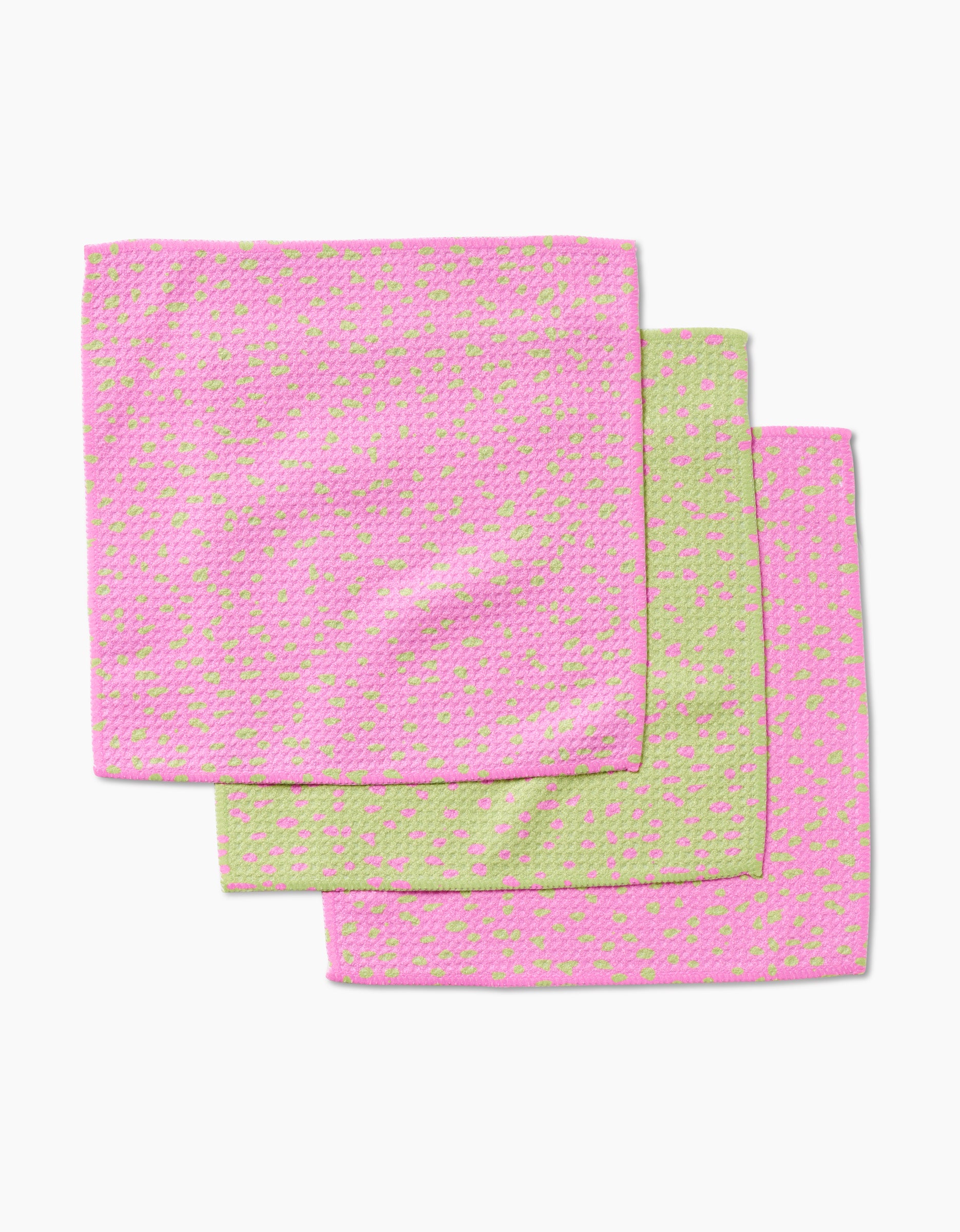 The GEOMETRY Speckle Green Pink set includes three square dishcloths in super-absorbent Geoweave fabric: two pink with green dots and one green with pink dots, each featuring a stylish textured pattern.
