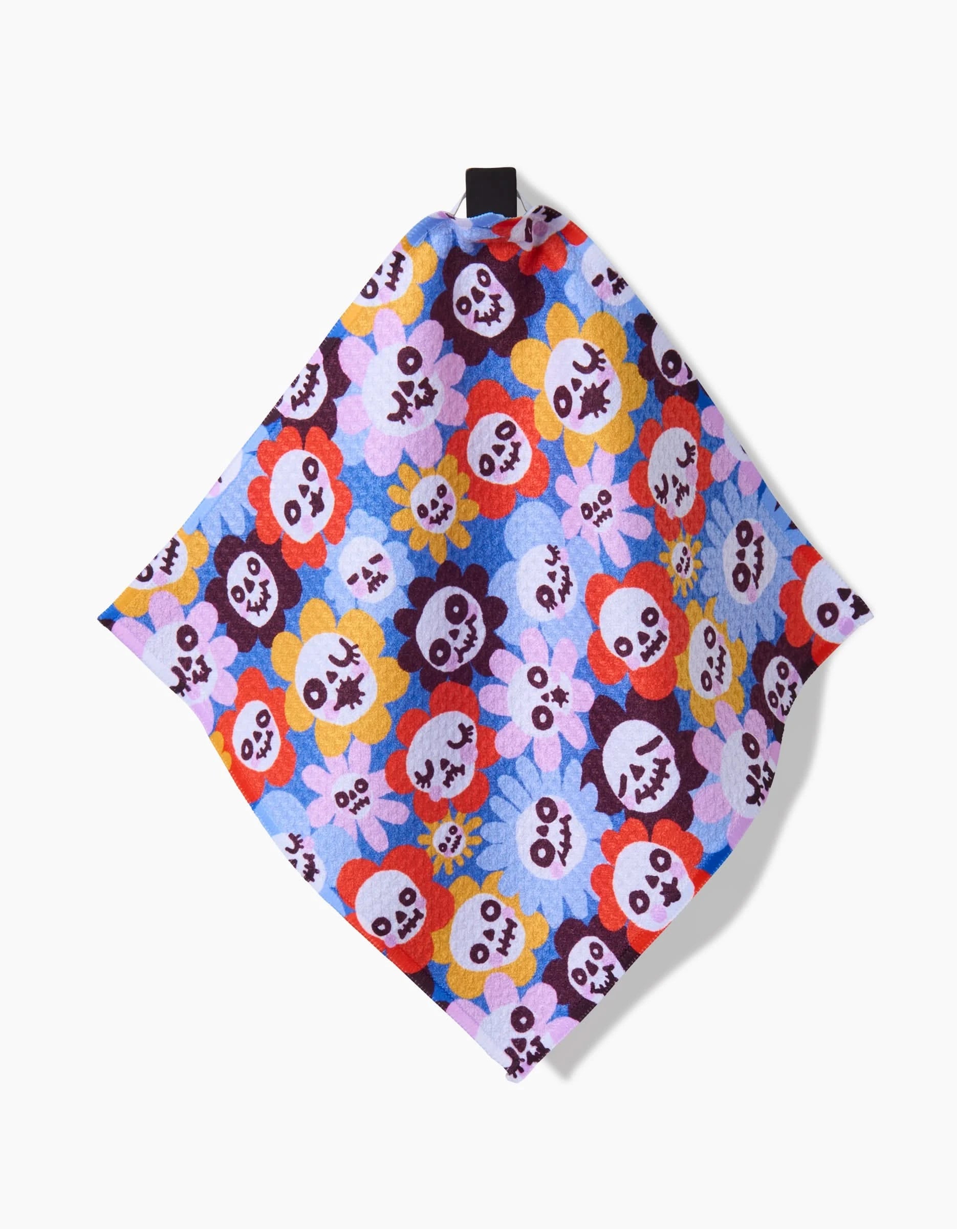 The So Lazo Spooky Bouquet dishcloth set features cartoon skulls and flowers in bright colors on light blue. Made from recycled materials, it’s shown diagonally with a black hanging loop at the top.