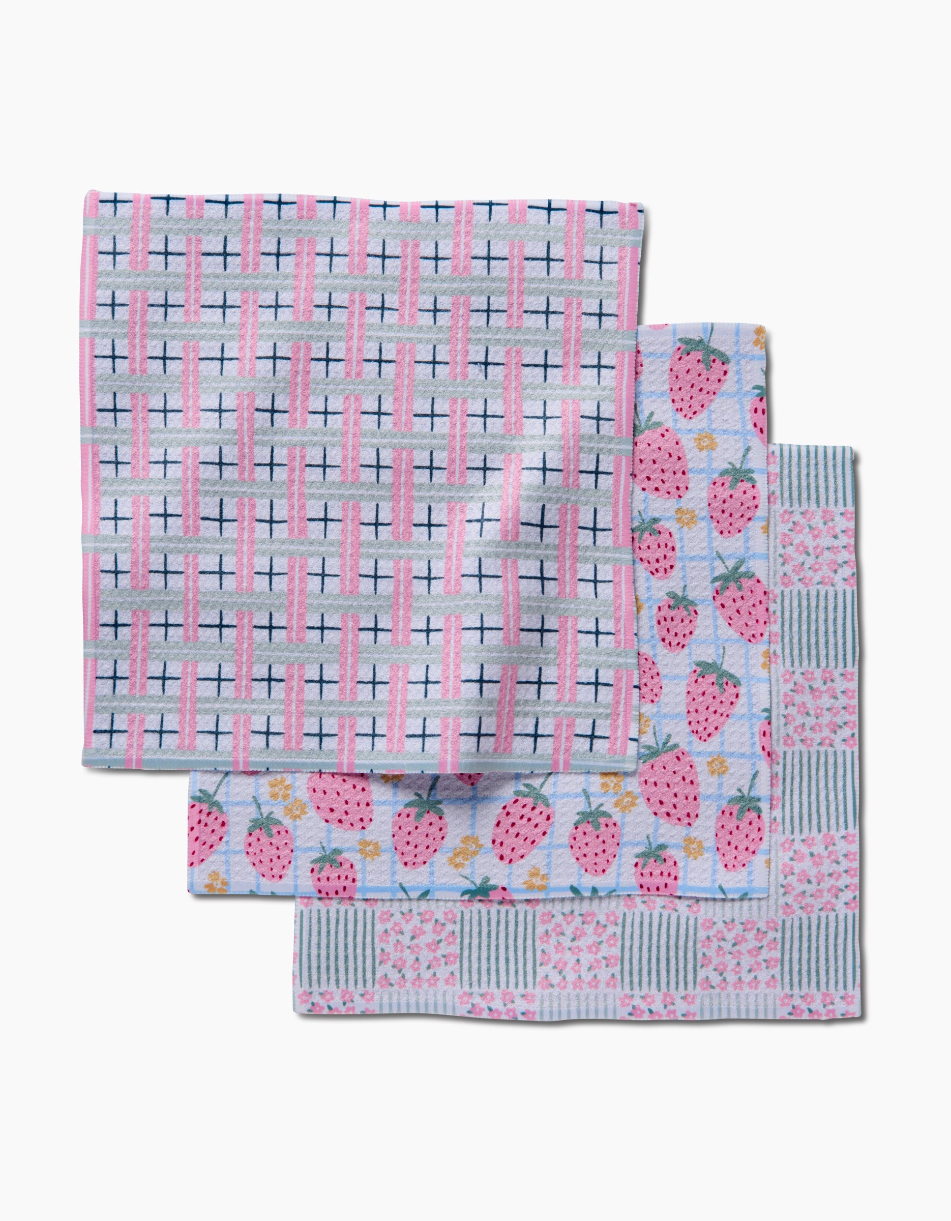 Three folded washcloths from Hufton Studios Spring Picnic Day Dishcloth Set, crafted from Geoweave fabric: one pink and blue grid, one pink strawberries, and one with blue-green squares and pink floral accents on a light background.
