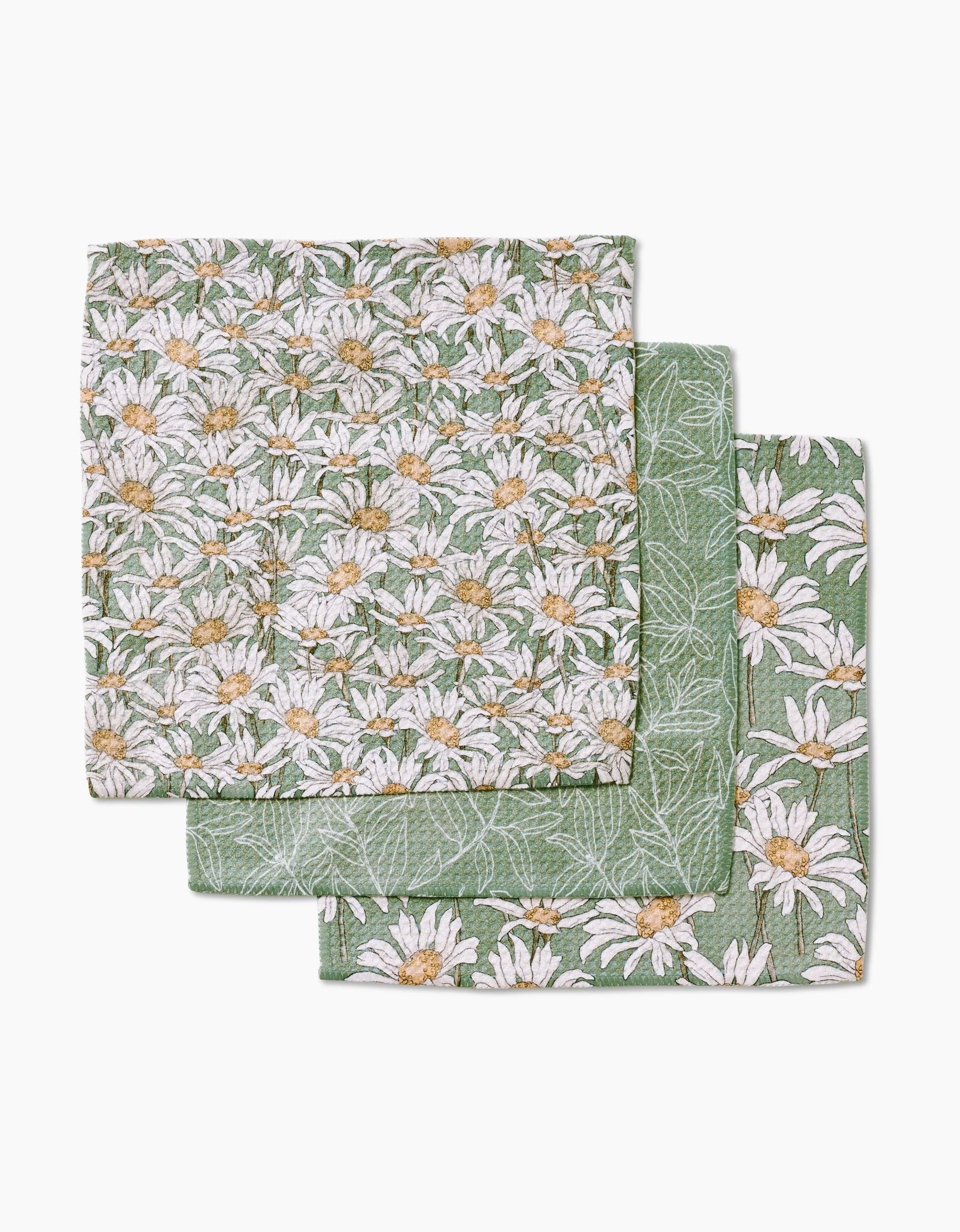 Three folded Springtime cloth napkins by Aubrey Fairchild, crafted from super-absorbent Geoweave fabric, display a green background with white daisy patterns and are stacked slightly offset.