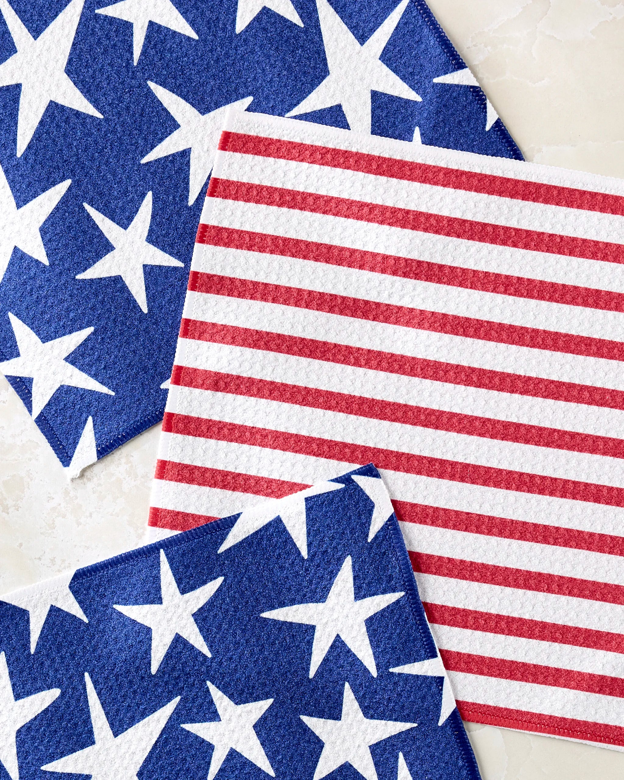 The Mindfulnice Stars And Stripes set includes three dishcloths: two with blue and white stars, one with red and white stripes (flag-inspired). All are made from recycled materials.