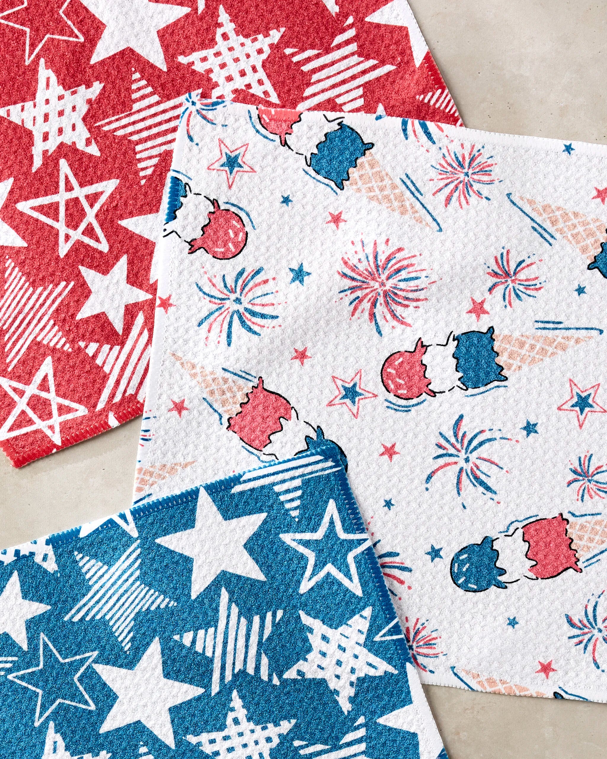 The Hufton Studio Stars In Your Eyes set includes three festive paper napkins: red with white stars, blue with white stars, and white decorated with patriotic pops, fireworks, and stars—perfect for pairing with a dishcloth set.