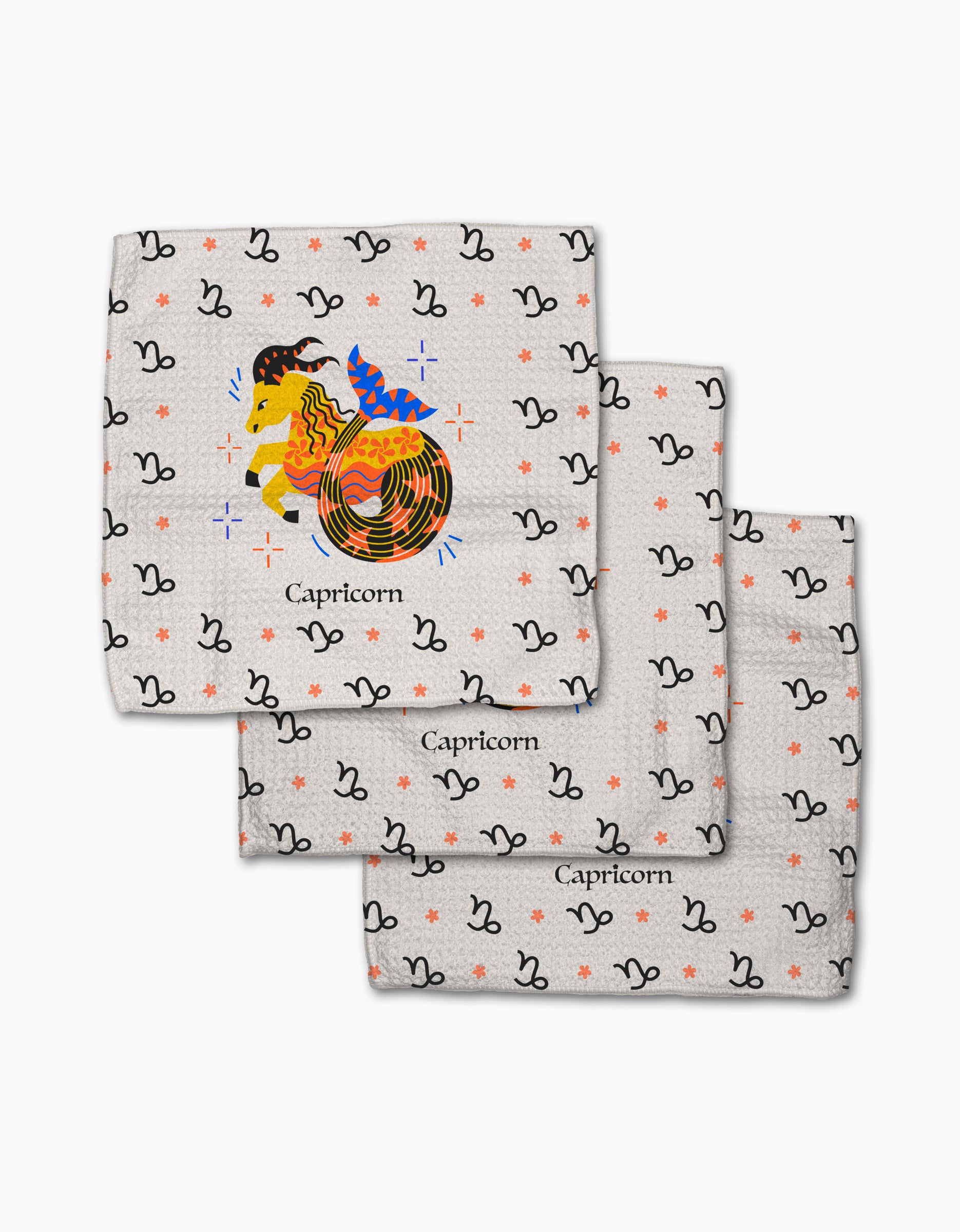 The Steadfast Capricorn dishcloth set by Heather Zhou includes three patterned cloths, each with colorful Capricorn zodiac symbols on white, black accents, and orange stars. Made from recycled materials.