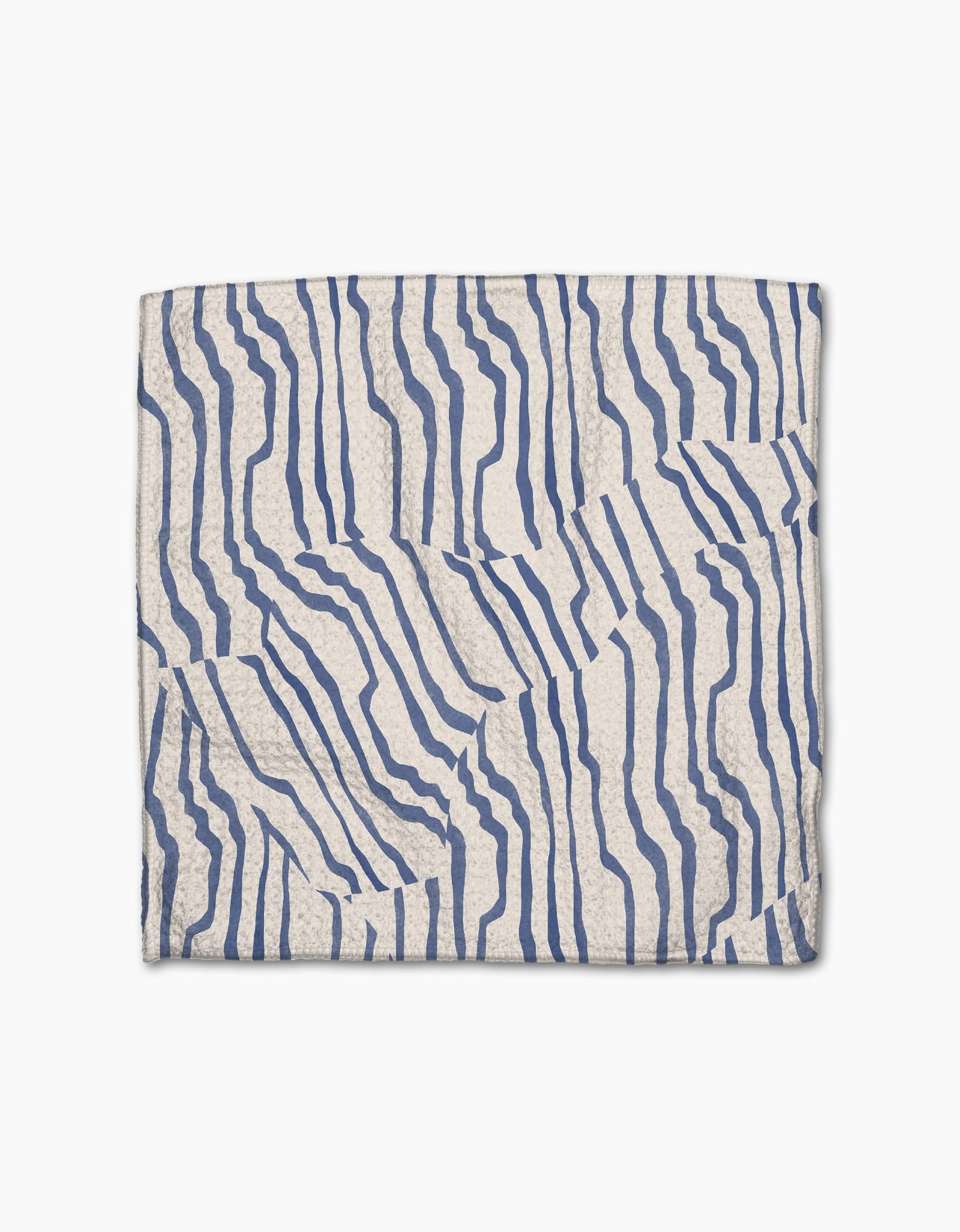 The Geometry Stripe Funk Grounds napkin features a folded white Geoweave fabric with an abstract blue wavy line pattern forming an irregular, striped design on a plain white background.
