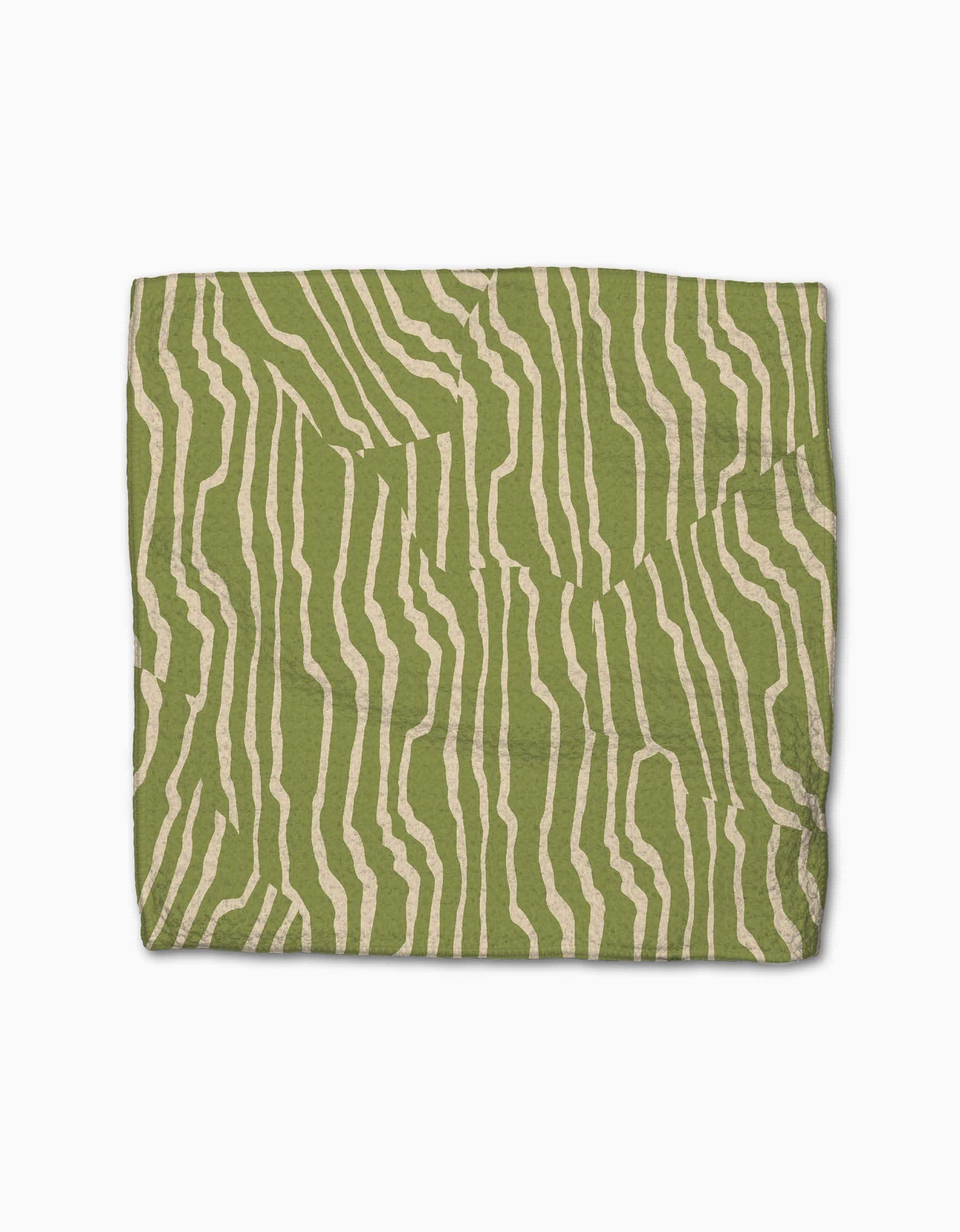 The Geometry Stripe Funk Grounds Green blanket is a rectangular, eco-friendly throw made from recycled materials, featuring an abstract cream wavy stripe pattern on a green backdrop.