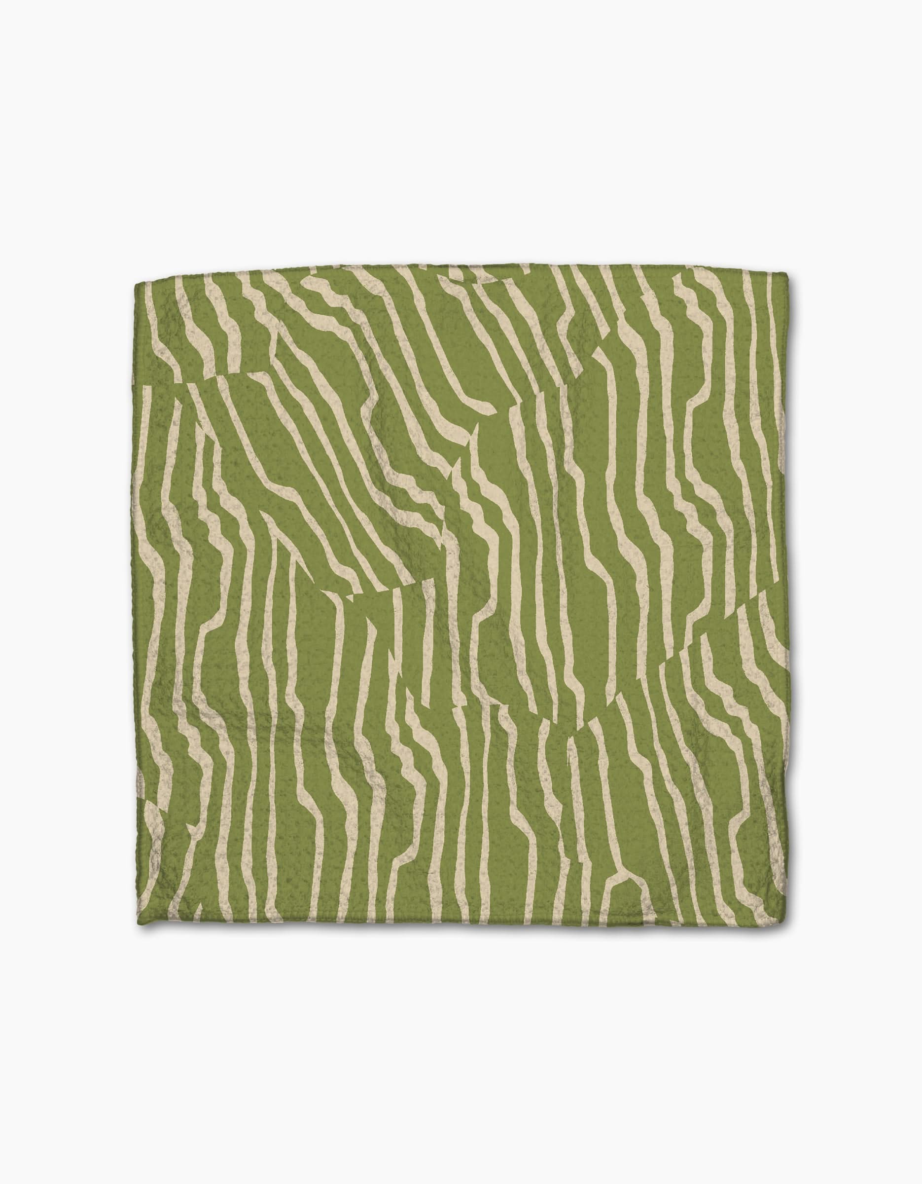 Geometry’s Stripe Funk Grounds Green quilt, crafted from recycled materials, features abstract cream wavy stripes on green, resembling zebra stripes. Displayed against a white background.