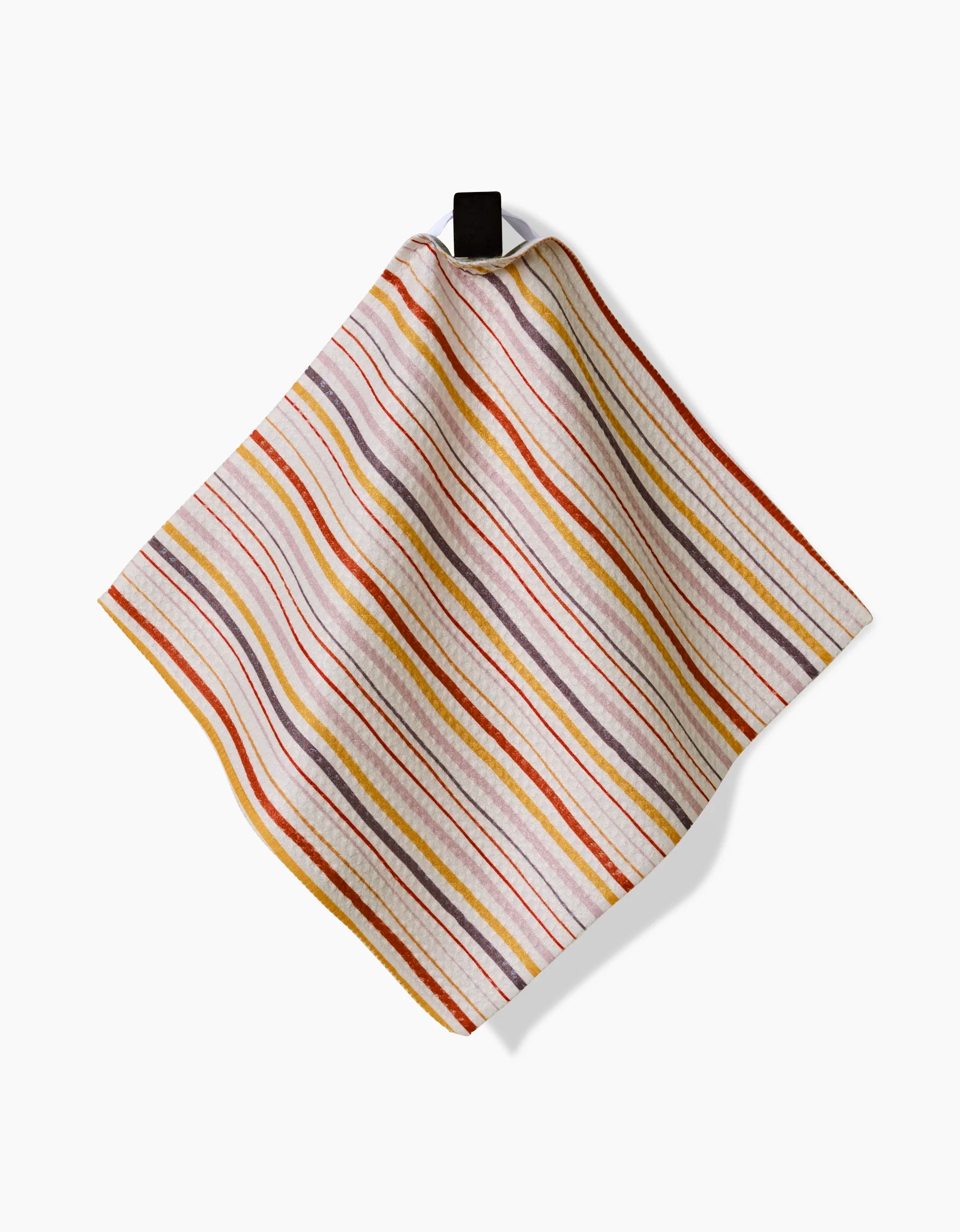 The GEOMETRY Stripe Season napkin is a square cloth made from recycled materials, featuring red, orange, yellow, and gray diagonal stripes. It hangs from a black loop against a white background.
