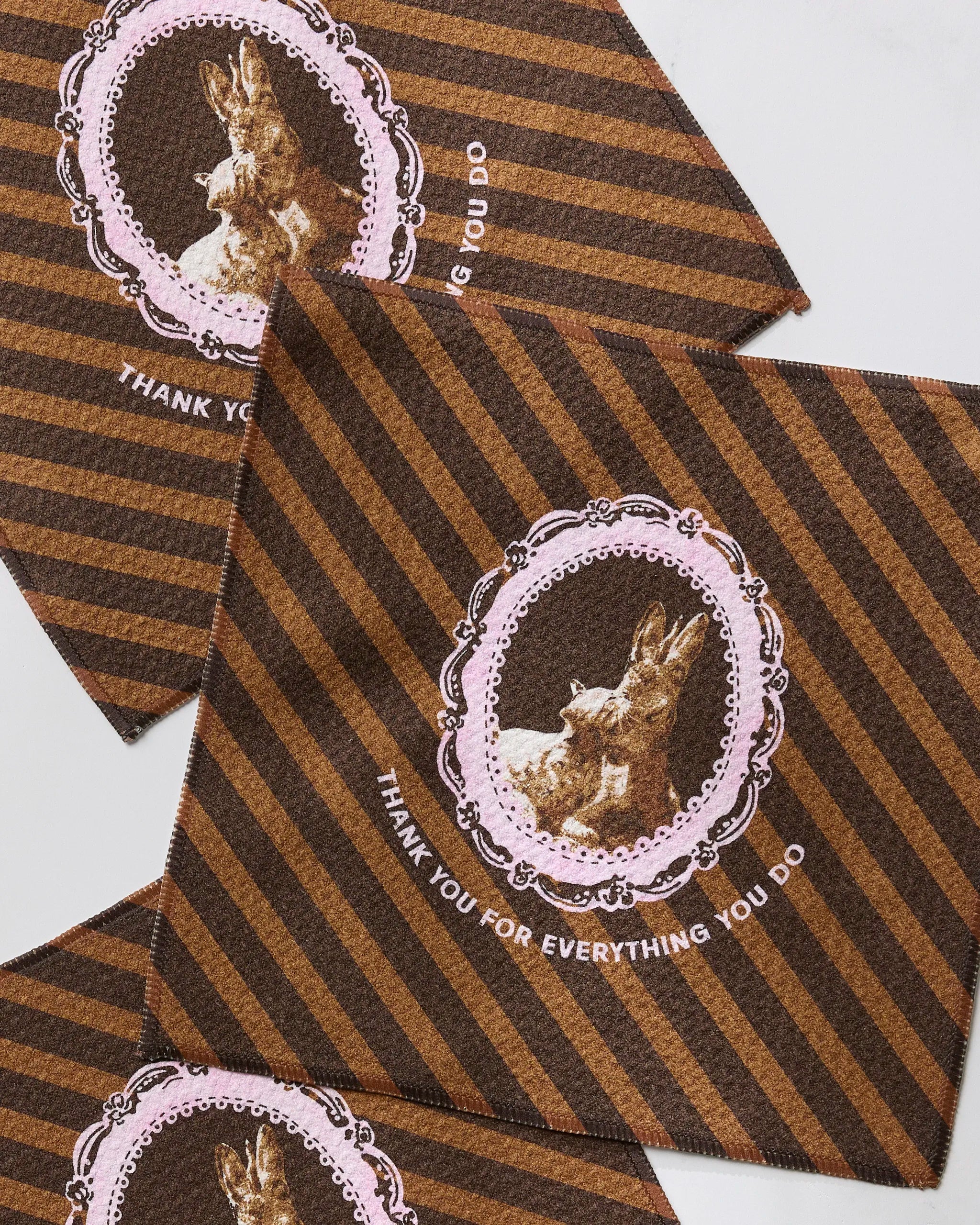 Geometry’s Strong and Caring cloths, made from recycled materials, feature brown stripes and a vintage-style rabbit framed in pink lace with “THANK YOU FOR EVERYTHING YOU DO” below the image.