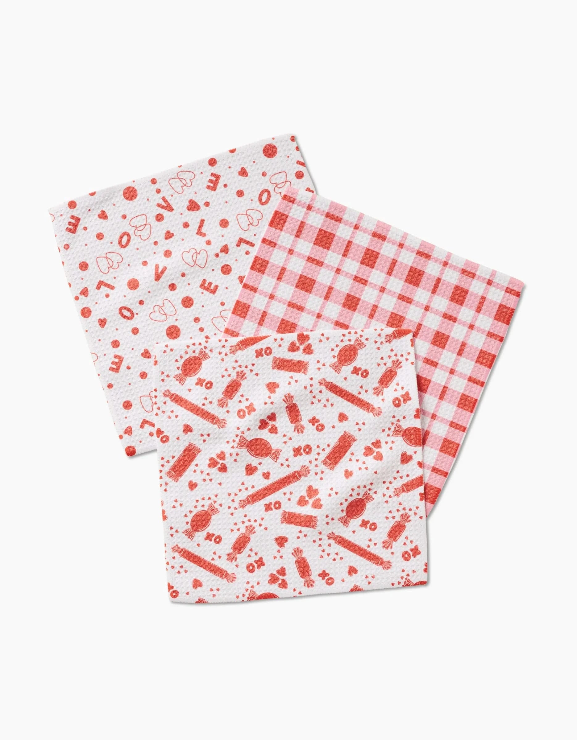 Charlie Rowan Designs Sweet Love set displays three Geoweave reusable dishcloths: one with red holiday patterns, one with a red and white checkered design, and a third featuring red shapes and icons on white.