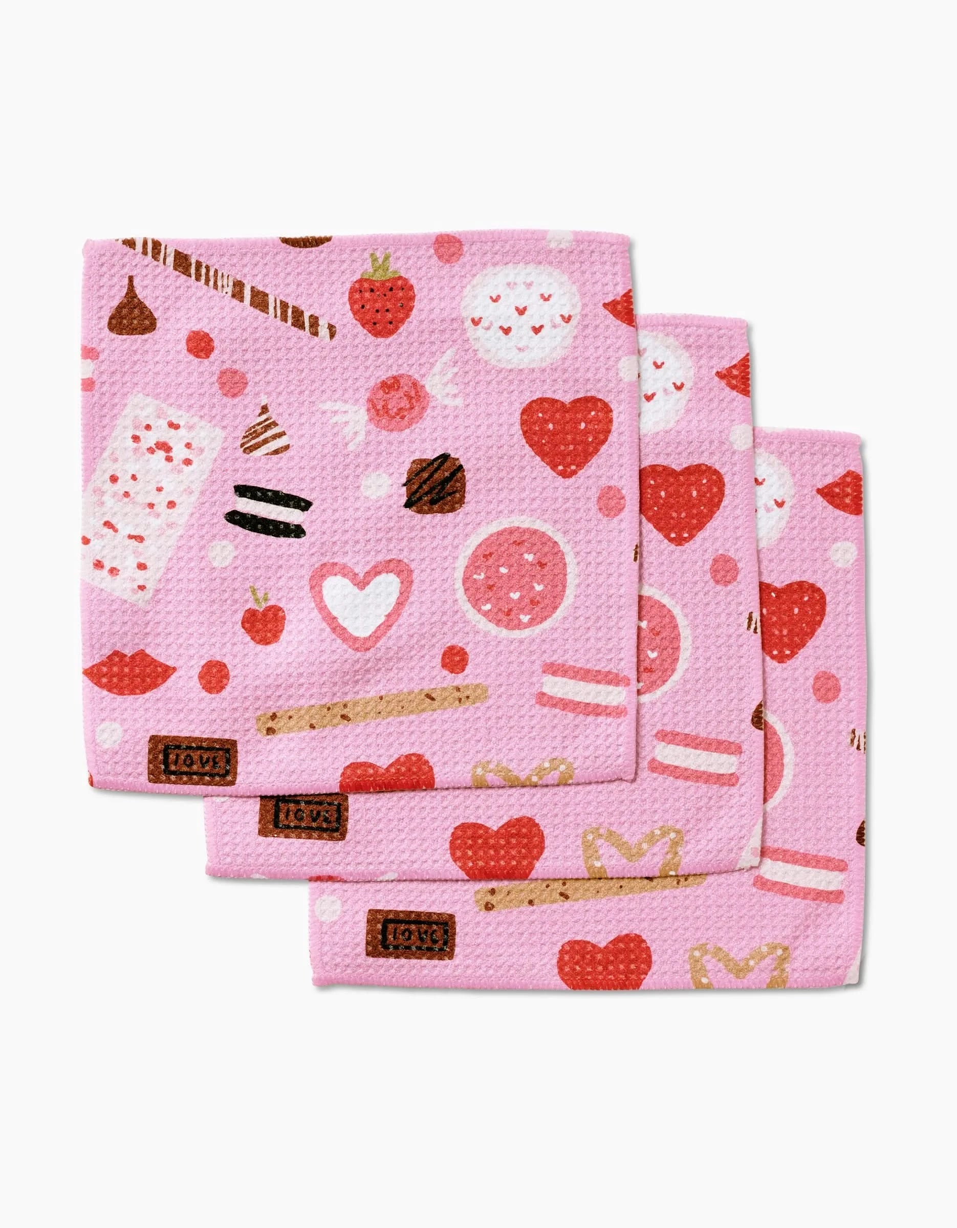 Janna Sue Design’s Sweet Lovin set includes three pink Geoweave dishcloths with playful hearts, strawberries, and treats in red, white, and brown for a cute, whimsical touch.