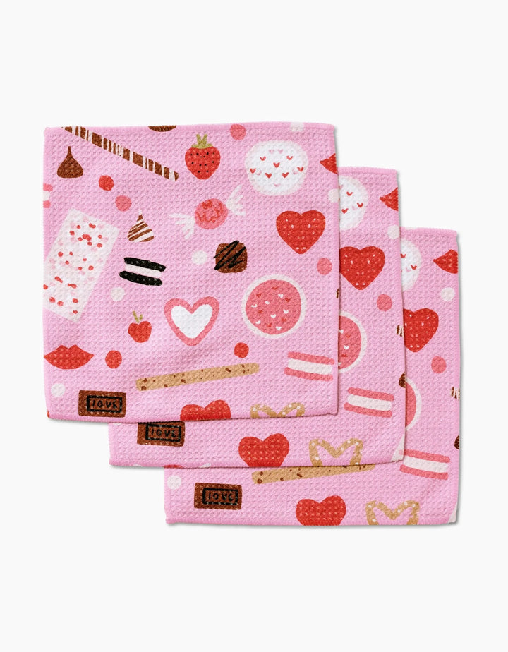Janna Sue Design’s Sweet Lovin set includes three pink Geoweave dishcloths with playful hearts, strawberries, and treats in red, white, and brown for a cute, whimsical touch.