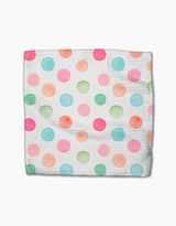 A Sweet Macarons cloth napkin by Elena Fay features a white Geoweave fabric adorned with watercolor polka dots in pink, blue, green, and orange, laid flat on a white background.