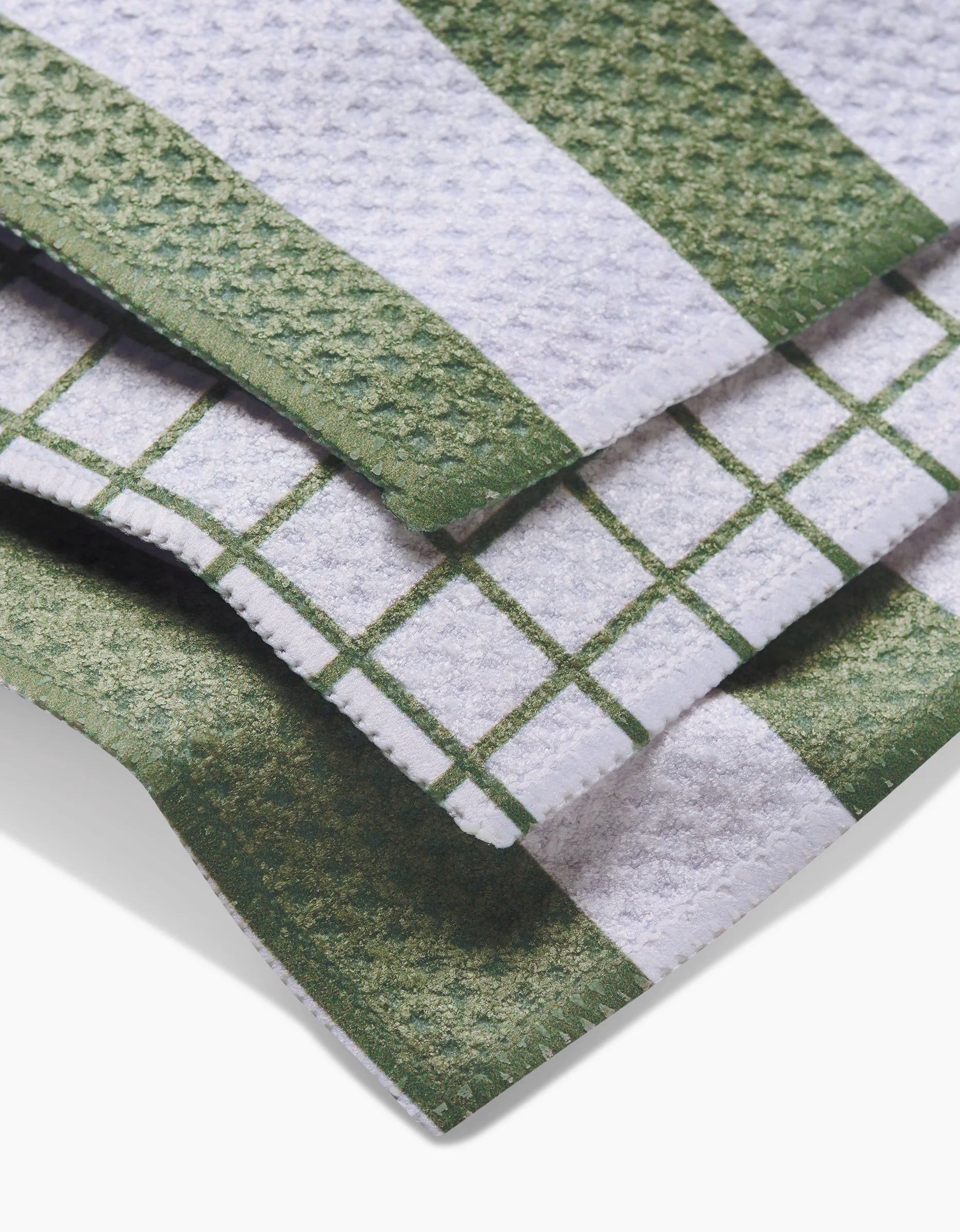 Three Sweet Mint kitchen towels by Kailee Wright are stacked, each in green and white with solid, striped, and checkered patterns. Made from eco-friendly Geoweave fabric, these dishcloths have a durable, textured surface.
