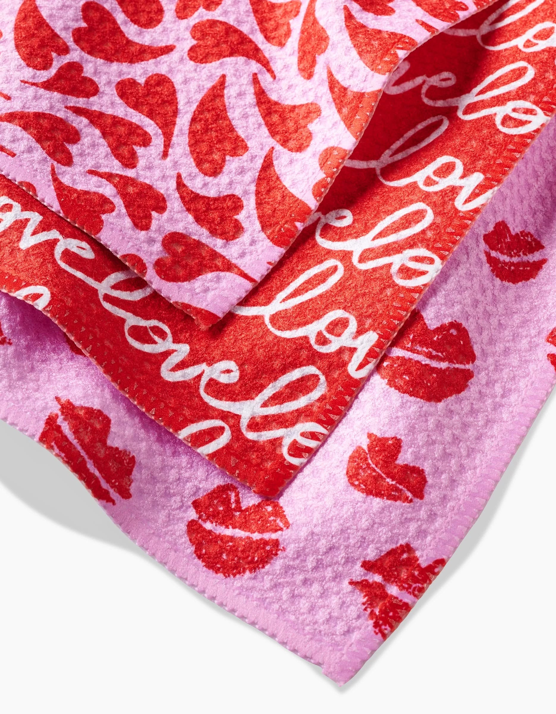 The Swooning Hearts dishcloth set by Kayla Ann features three Geoweave cloths with textured surfaces: one pink with red lips, one red with white “love” text, and one pink with hearts and lips—perfect for Valentine’s Day.