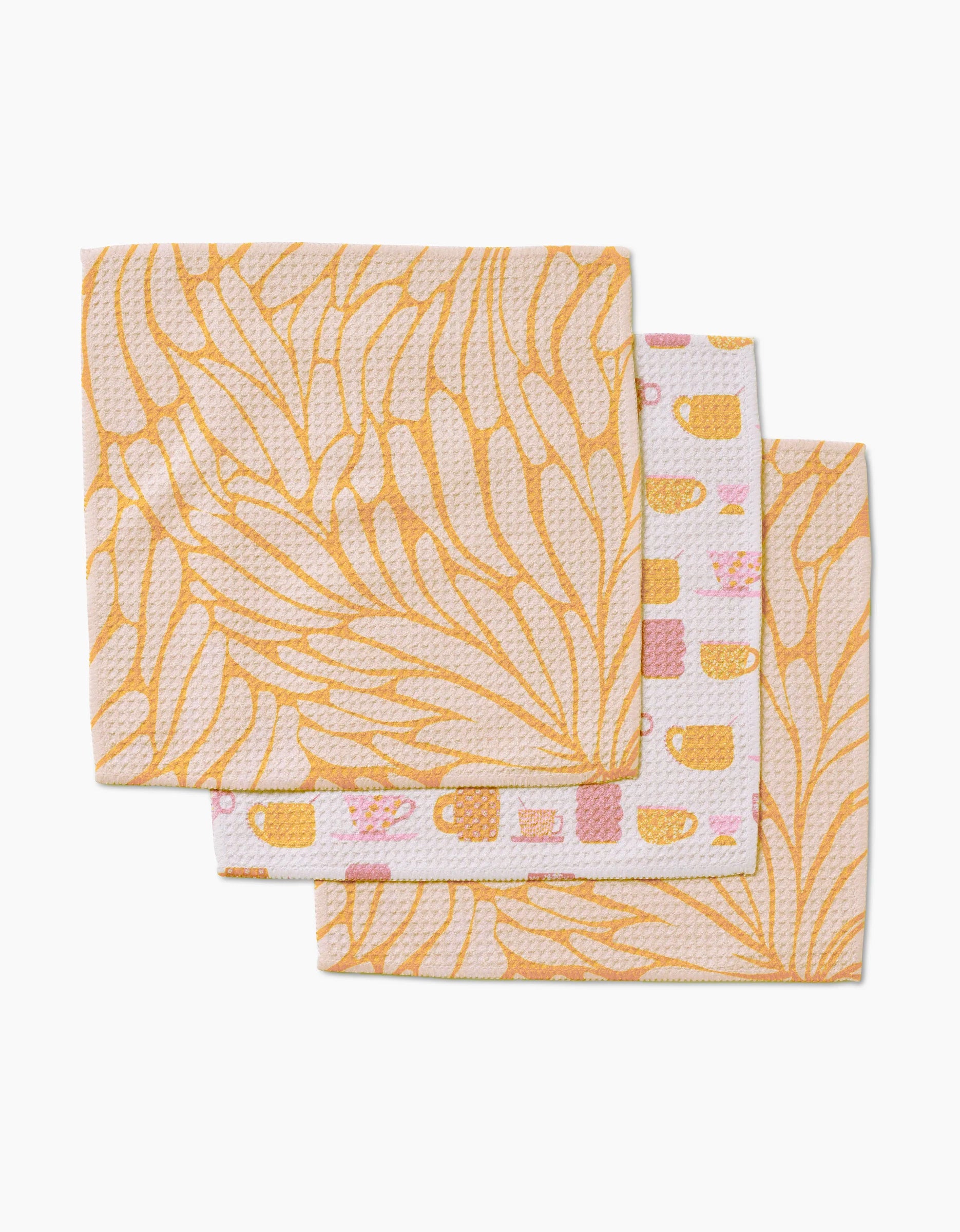 Three reusable GEOMETRY Tenderhearted dishcloths stacked: two with pastel yellow leafy patterns, one with pink & yellow teacups and squares on white—crafted from premium Geoweave fabric.