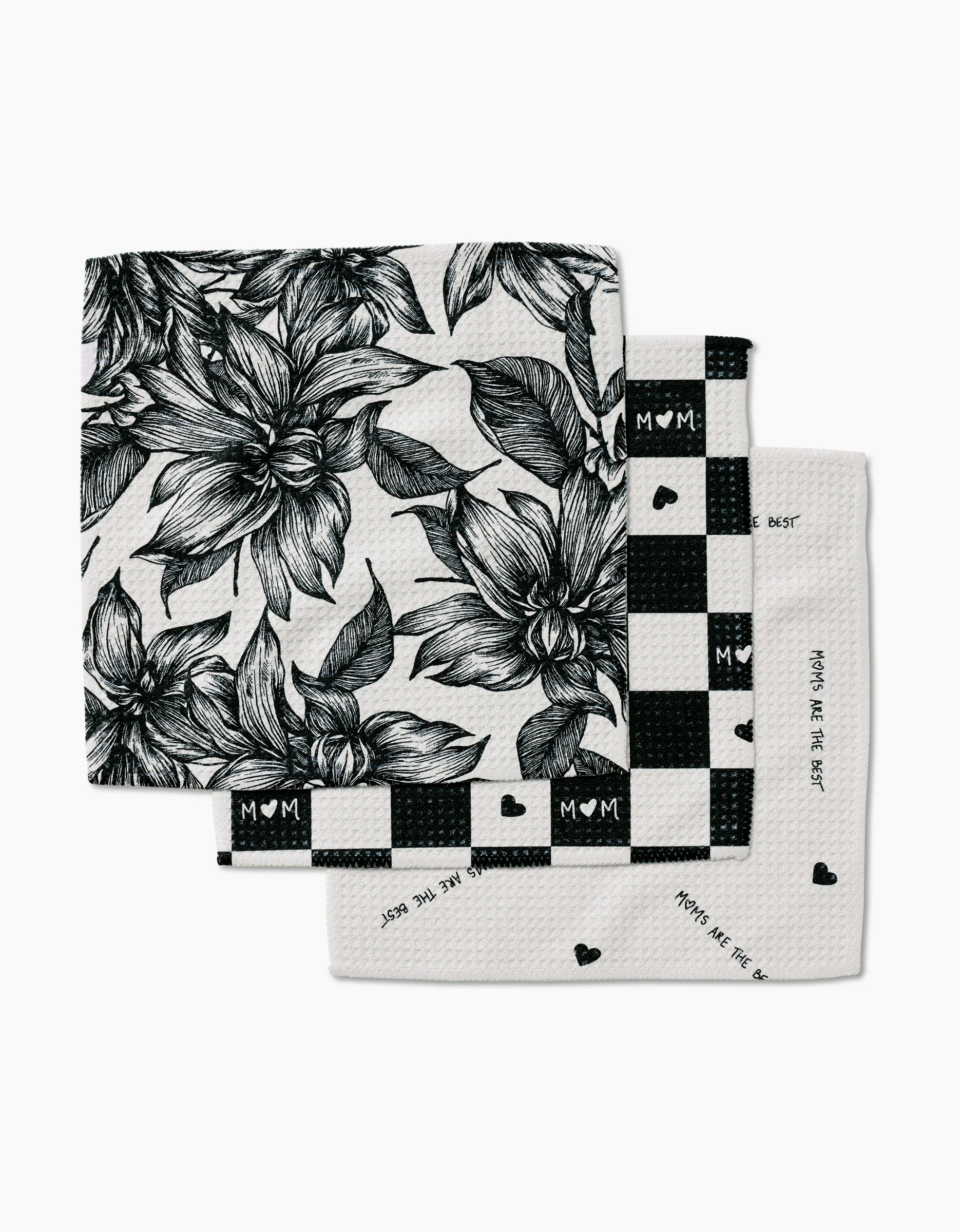 The Best Dishcloth Set by GEOMETRY includes three folded napkins made from recycled materials: one with a black floral print, one with a black-and-white “MOM” checkered design, and one featuring “Moms are the best.”.