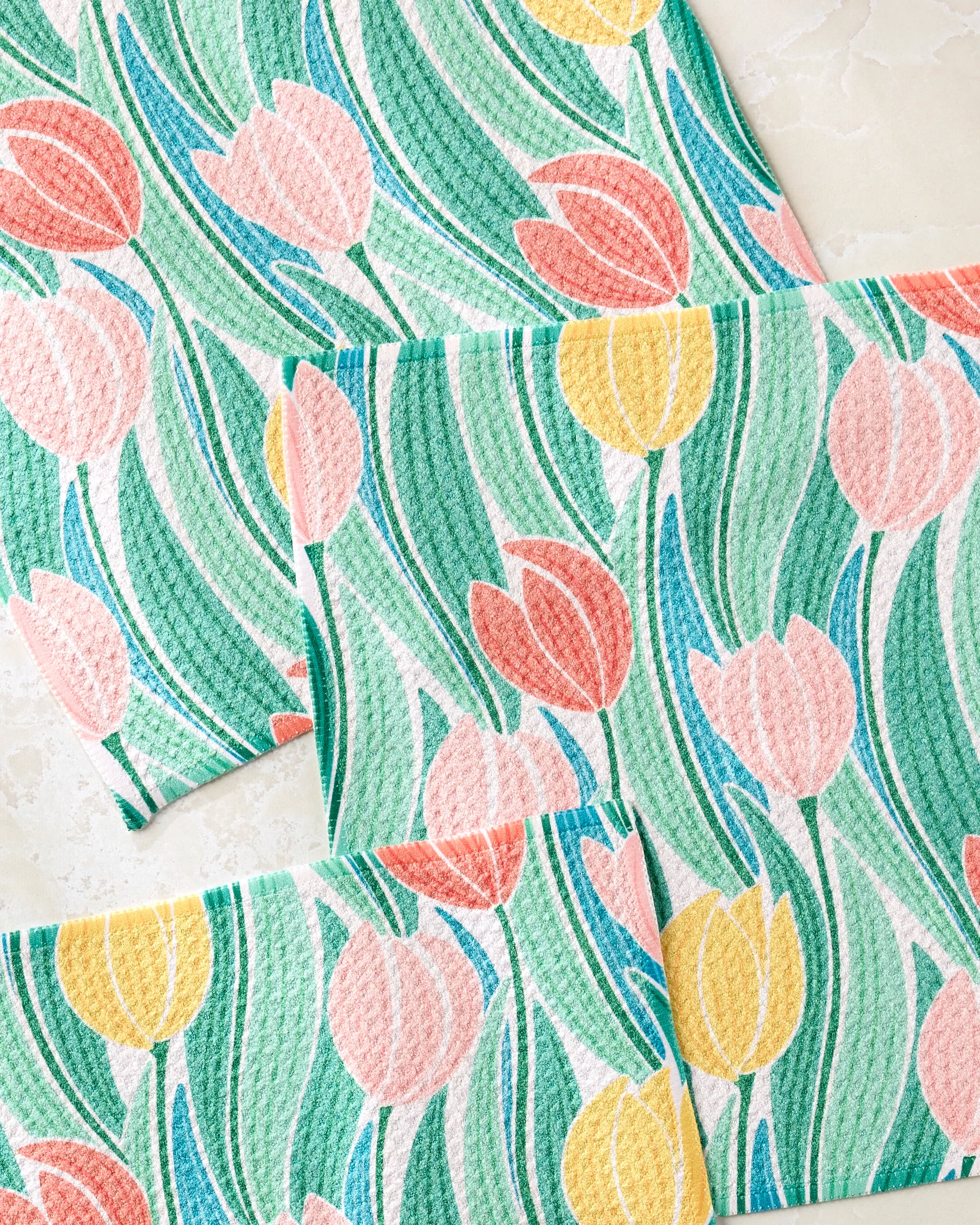 The Tranquil Tulips dishcloth set by Sarah Daugherty includes four rectangular, super-absorbent towels featuring colorful pink, yellow, and green tulip flowers with long curving leaves on a light background.