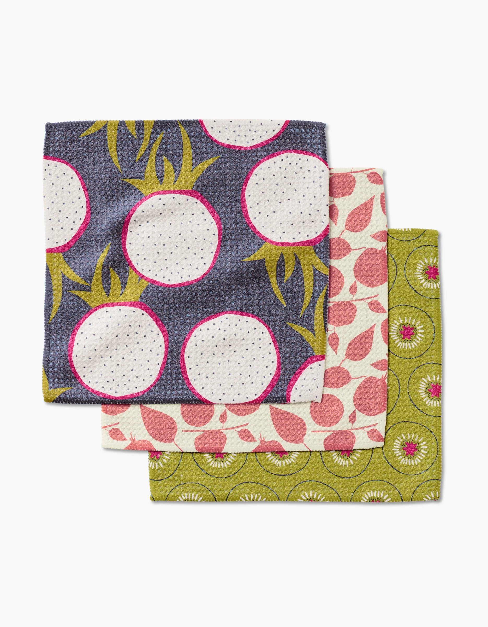 The Lizzie Clark Tropical Fruit Dishcloth Set includes three super-absorbent Geoweave towels in vibrant patterns: white radishes on dark blue, pink leaves on light pink, and green kiwi slices.