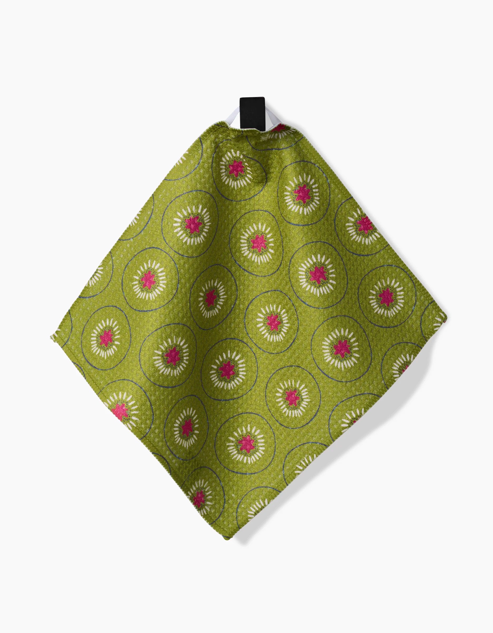 The Tropical Fruit cloth napkin by Lizzie Clark, made from Geoweave fabric, displays a repeating white and pink circular pattern on green and hangs by a black loop against a white background.