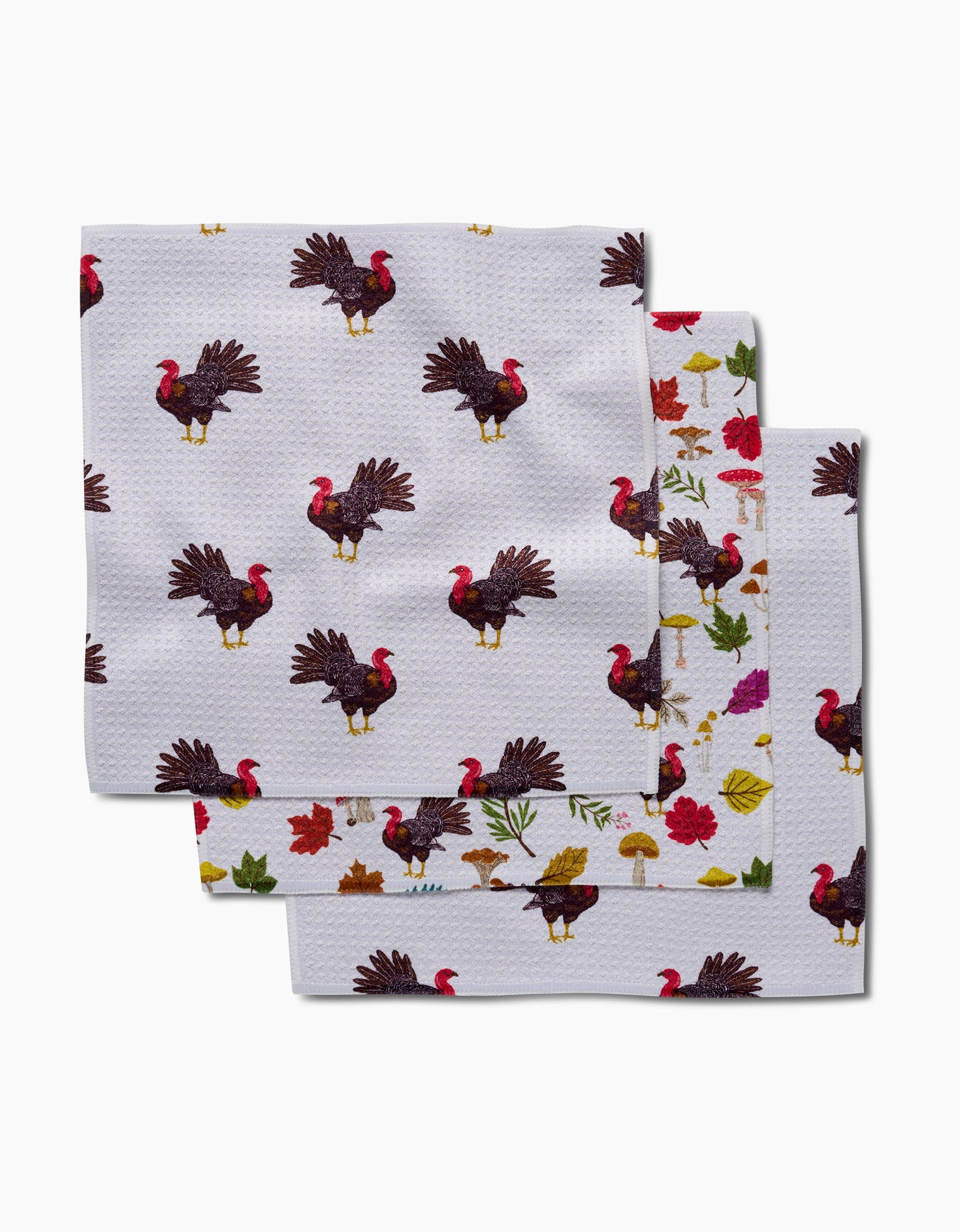 Vaishali Design Studio’s Turkey Day Parade features three eco-friendly napkins with festive Thanksgiving prints—turkeys, leaves, mushrooms, and flowers—on a white background, made from recycled materials.