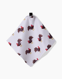 The Turkey Day Parade towel by Vaishali Design Studio is a white recycled cloth with a pattern of illustrated turkeys in various poses, hanging by a black loop against a white background.