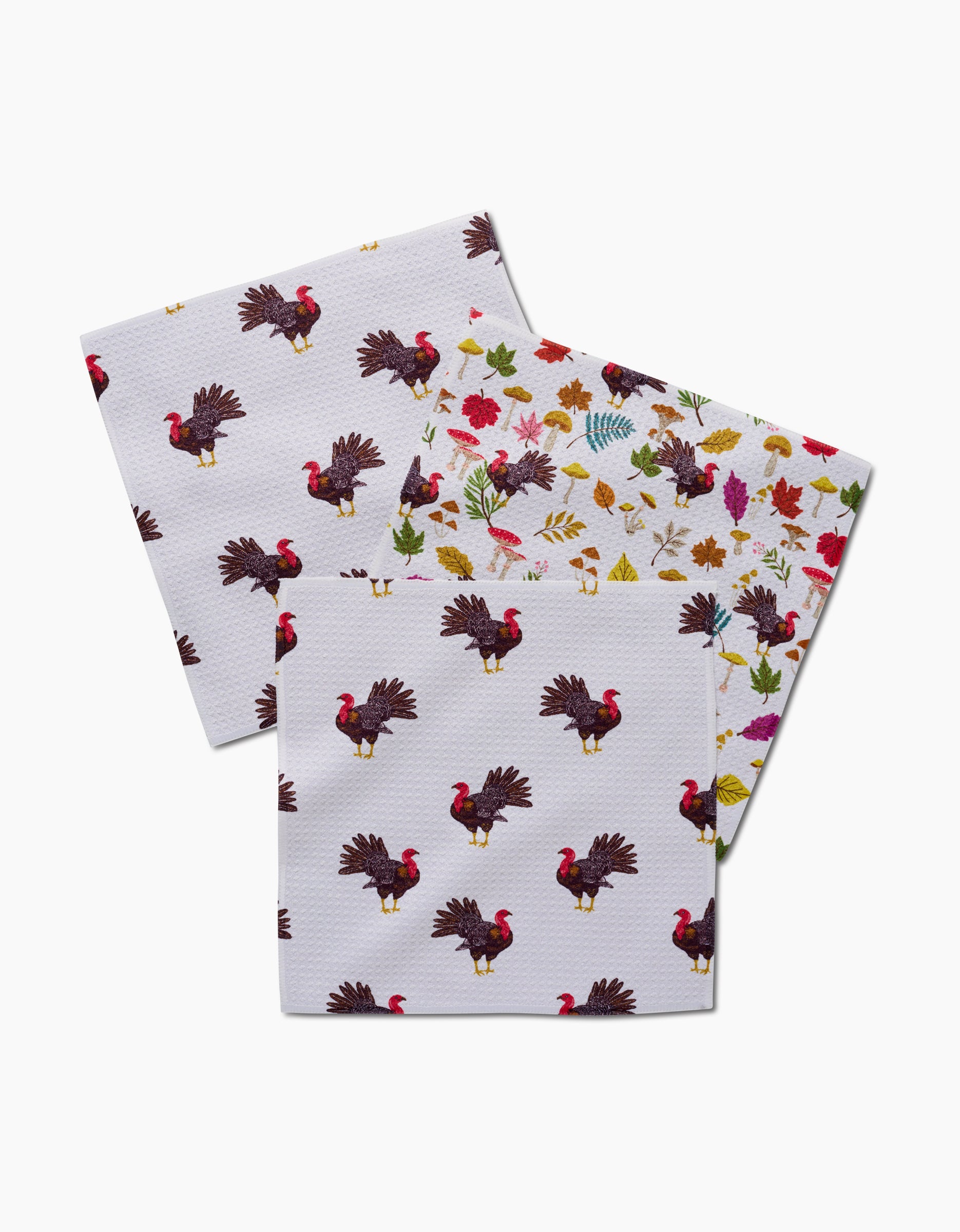 Vaishali Design Studio’s Turkey Day Parade includes three recycled paper napkins: two with a repeating turkey pattern and one with colorful autumn leaves, acorns, and berries, all displayed on a white background.